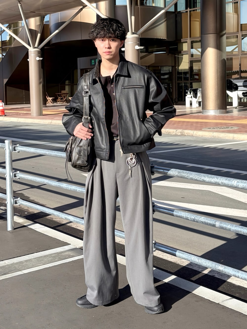 ブラック系のTシャツ/カットソー、ブラック系のデニムジャケット、グレー系のスラックスを着用したメンズの冬コーディネートの2枚目の写真