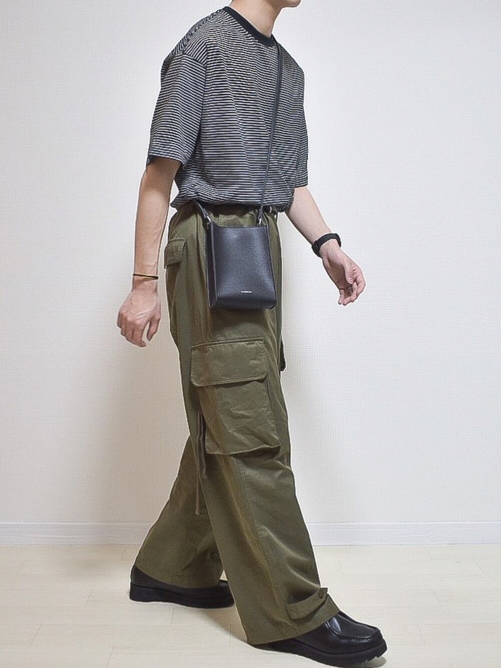ブラック系のTシャツ/カットソー、グリーン系のカーゴパンツ、ブラック系のローファーを着用したメンズの春コーディネートの3枚目の写真