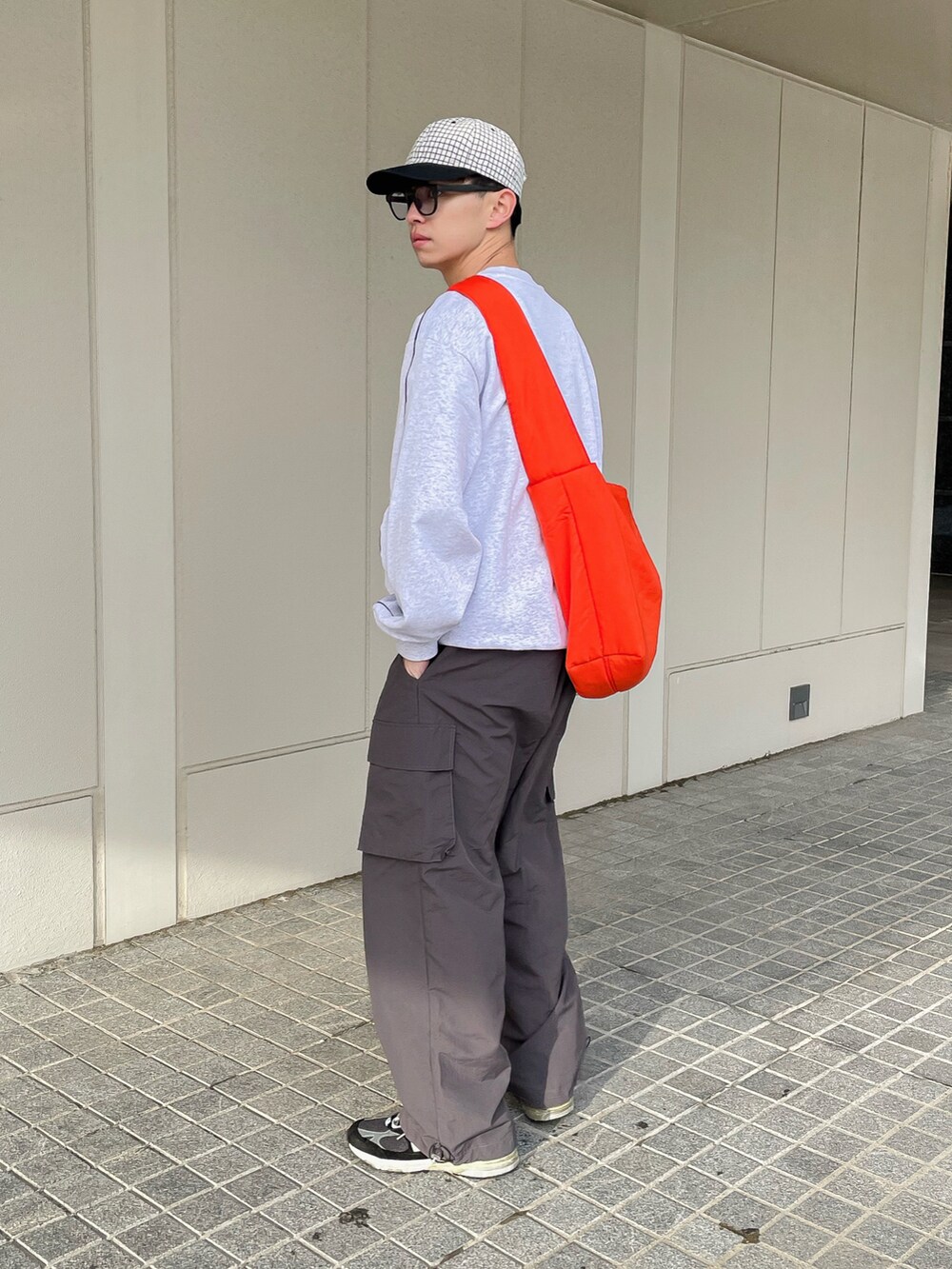 グレー系のスウェット、グレー系のカーゴパンツ、オレンジ系のショルダーバッグを着用したメンズの春コーディネートの4枚目の写真