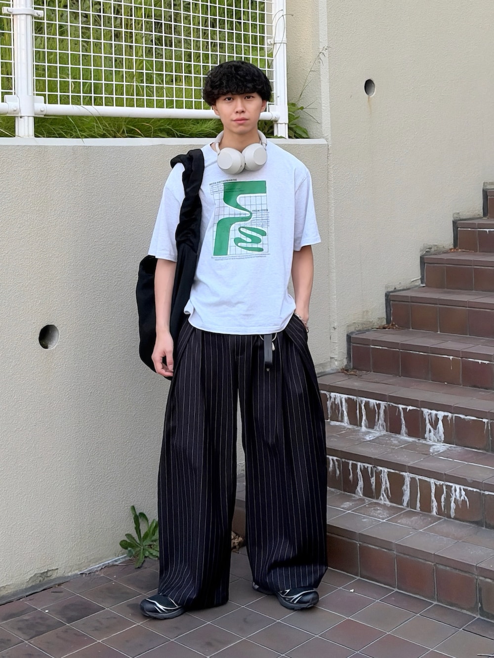 グレー系のTシャツ/カットソー、ブラック系のスラックス、ブラック系のショルダーバッグを着用したメンズの夏コーディネートの3枚目の写真