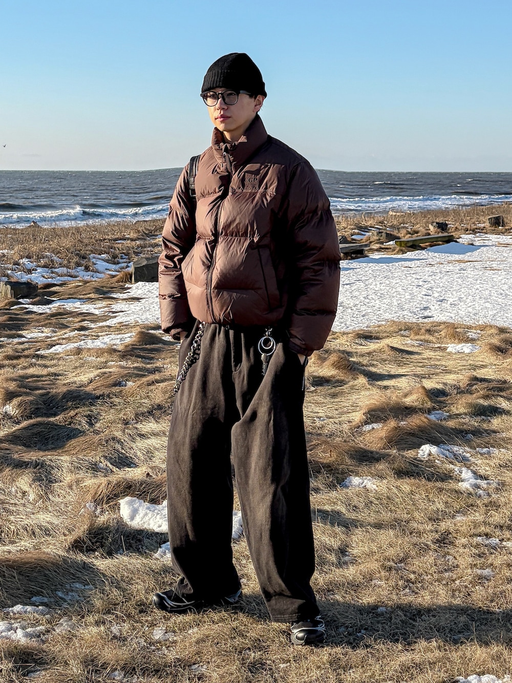 ブラウン系のダウンジャケット/コート、ブラック系のスウェットパンツ、ブラック系のスニーカーを着用したメンズの冬コーディネートの4枚目の写真