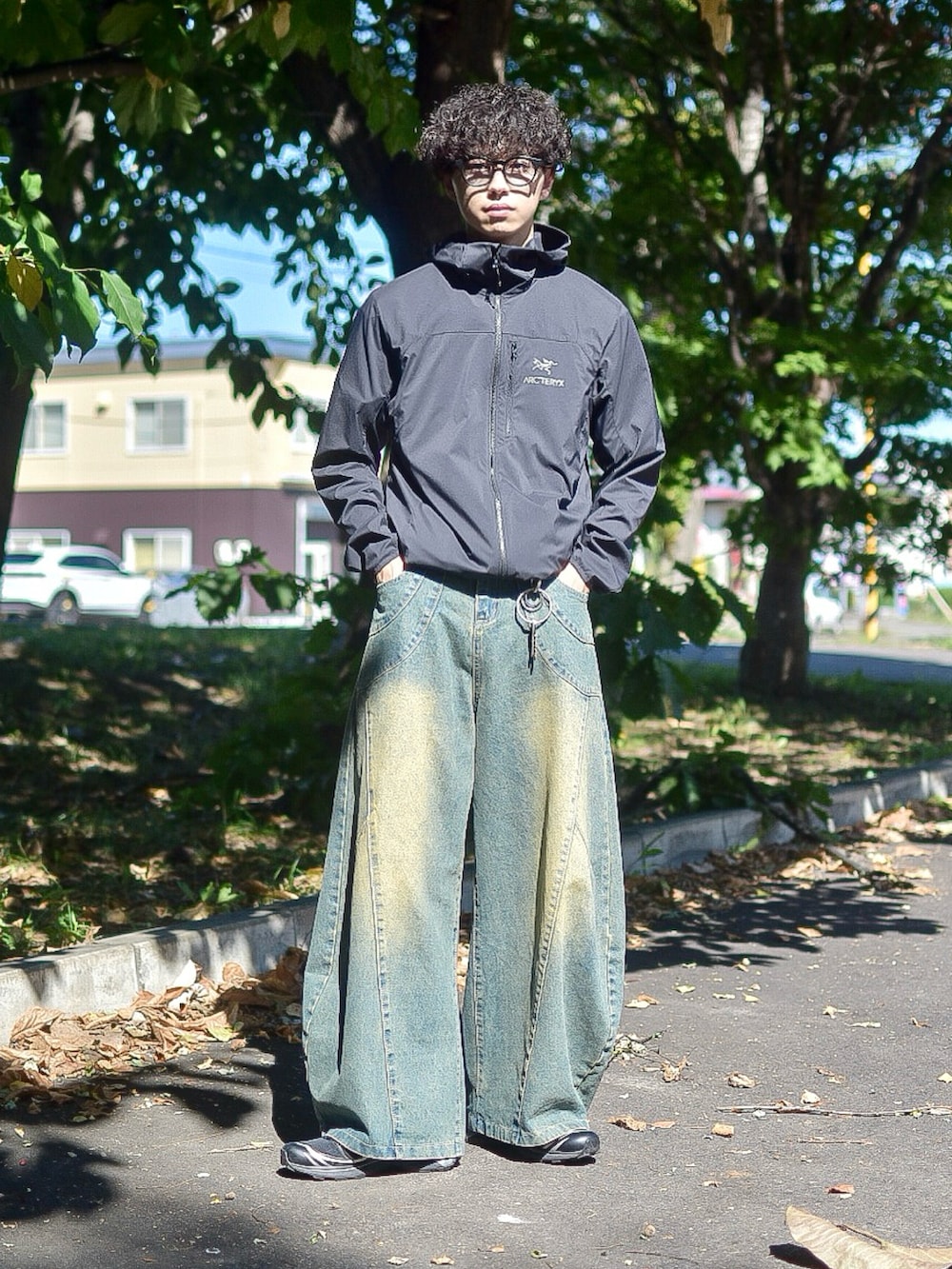 ブラック系のブルゾン、ブルー系のデニムパンツ、ブラック系のスニーカーを着用したメンズの秋コーディネートの2枚目の写真