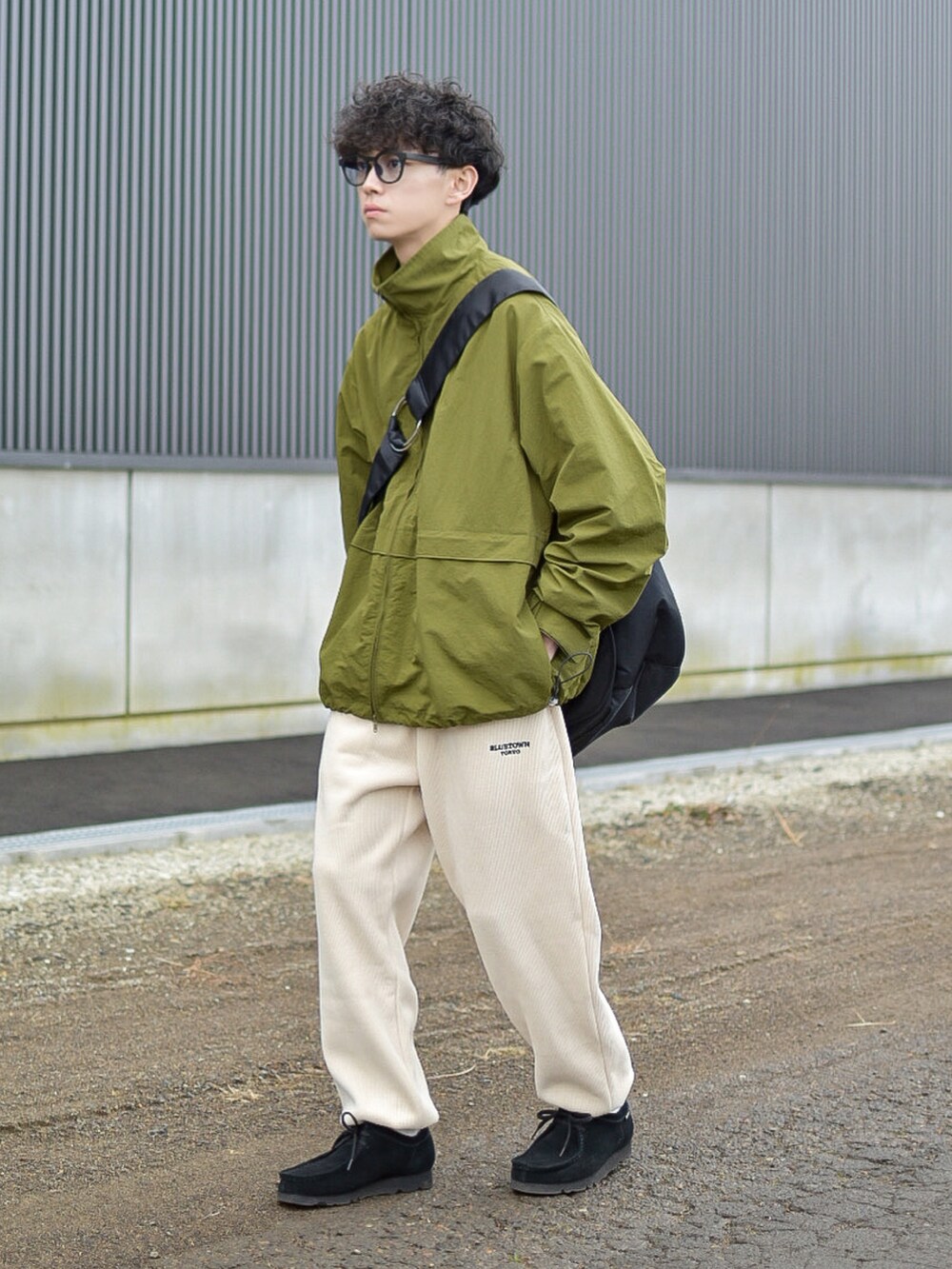 グリーン系のナイロンジャケット、ホワイト系のパンツ、ブラック系のショルダーバッグを着用したメンズの冬コーディネートの5枚目の写真