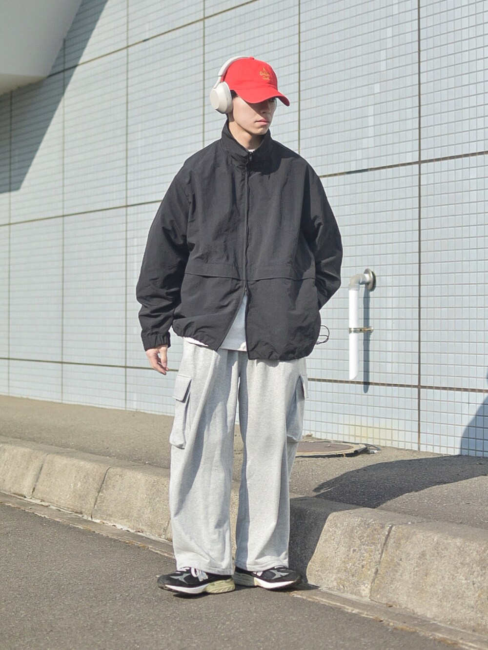 ブラック系のナイロンジャケット、グレー系のTシャツ/カットソー、グレー系のスウェットパンツを着用したメンズの春コーディネートの2枚目の写真