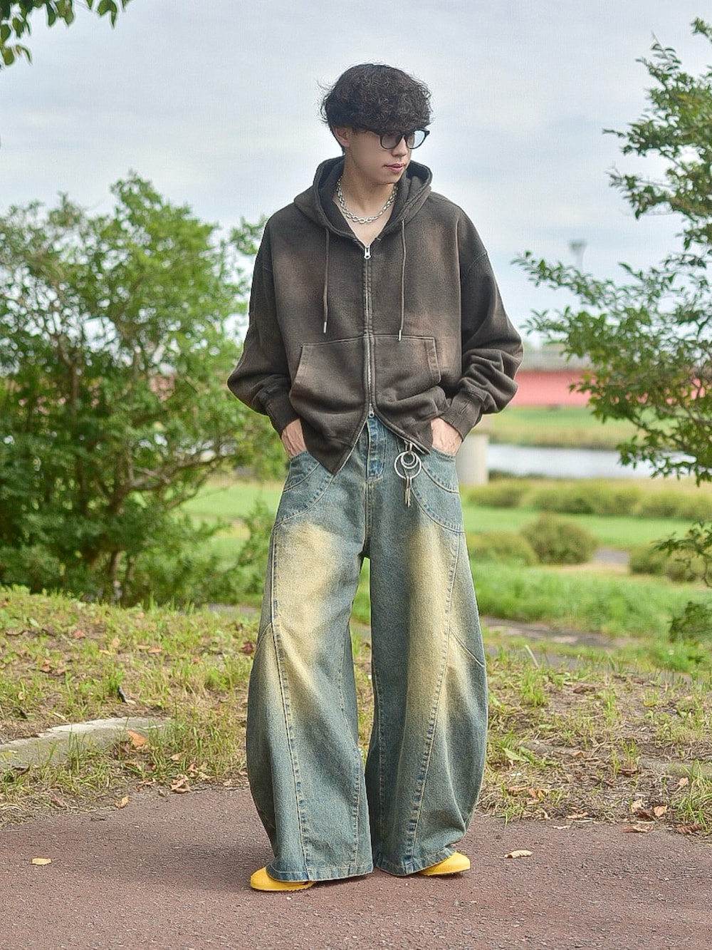 ブルー系のデニムパンツ、ブラウン系のパーカー、イエロー系のスニーカーを着用したメンズの秋コーディネートの2枚目の写真