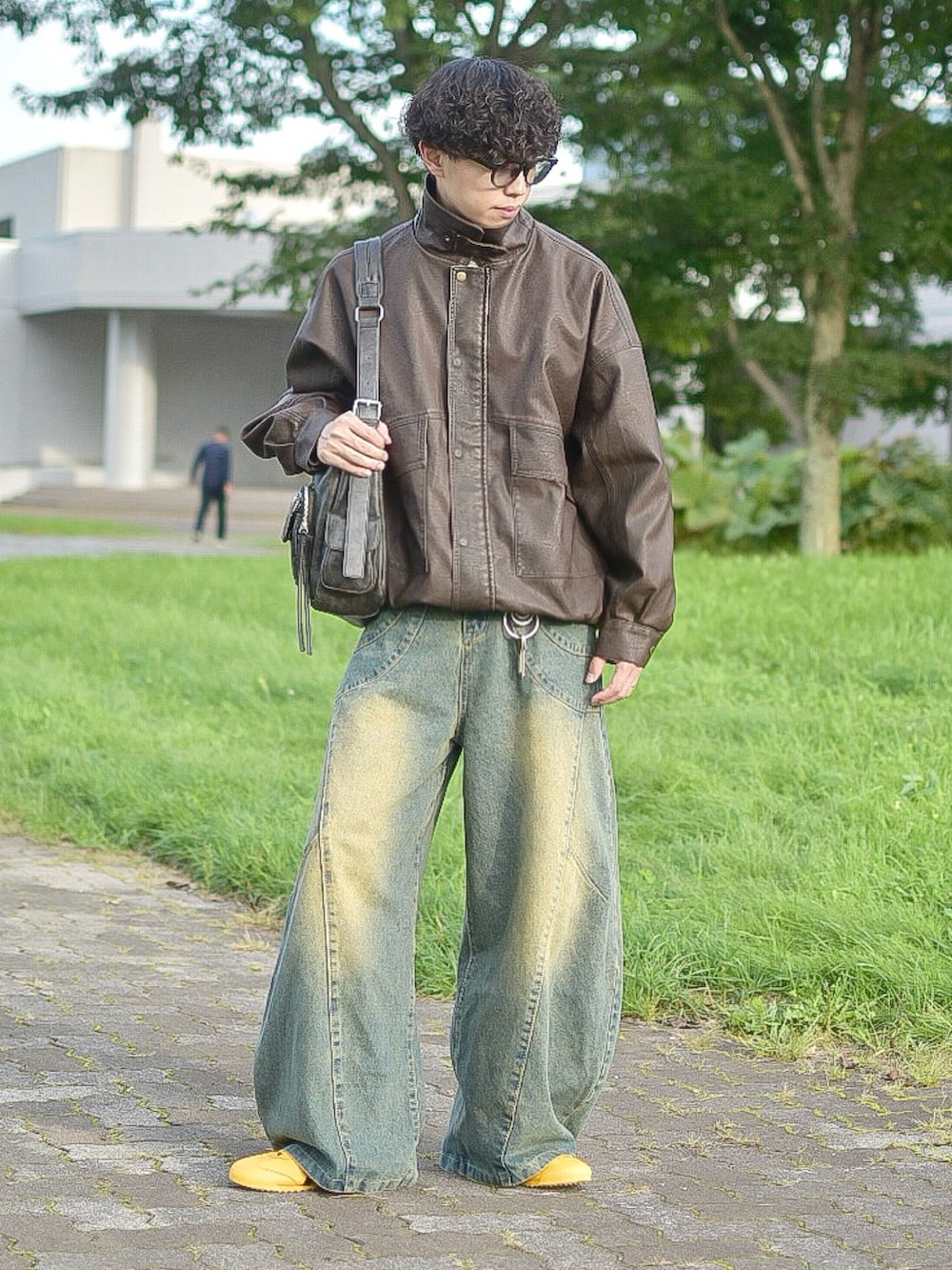 ブラウン系のブルゾン、ブルー系のデニムパンツ、イエロー系のスニーカーを着用したメンズの秋コーディネートの2枚目の写真