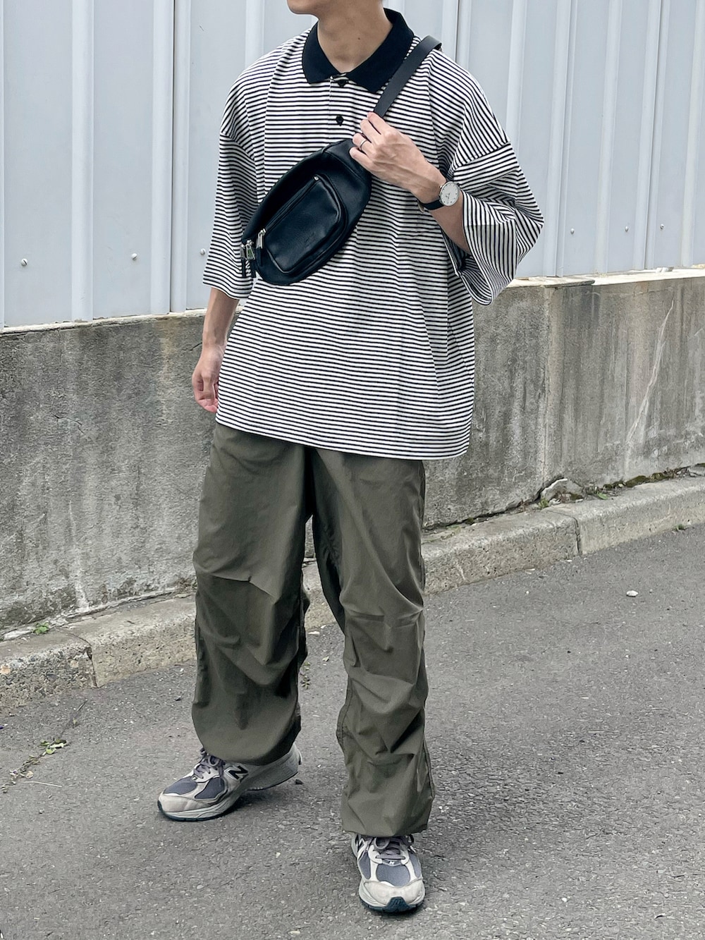 ブラック系のポロシャツ、ブラック系のボディバッグ/ウエストポーチ、グレー系のスニーカーを着用したメンズの夏コーディネートの4枚目の写真