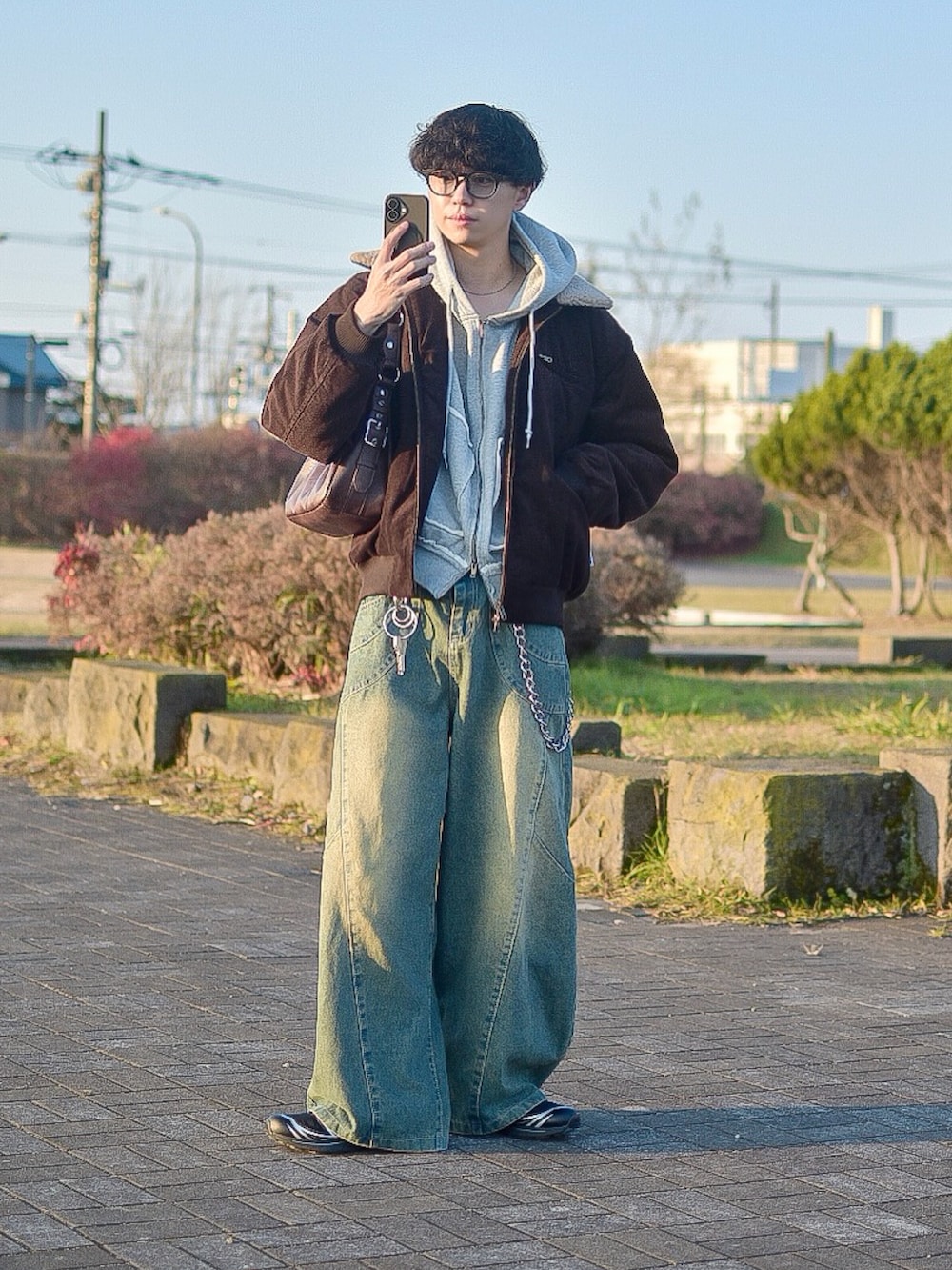 ブラウン系のブルゾン、ブルー系のデニムパンツ、グレー系のパーカーを着用したメンズの秋コーディネートの5枚目の写真