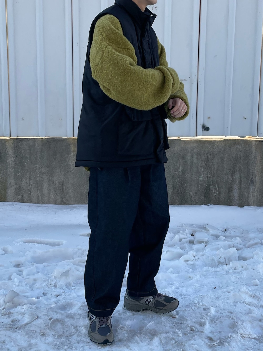 ブラック系のダウンベスト、グレー系のスニーカーを着用したメンズの冬コーディネートの2枚目の写真