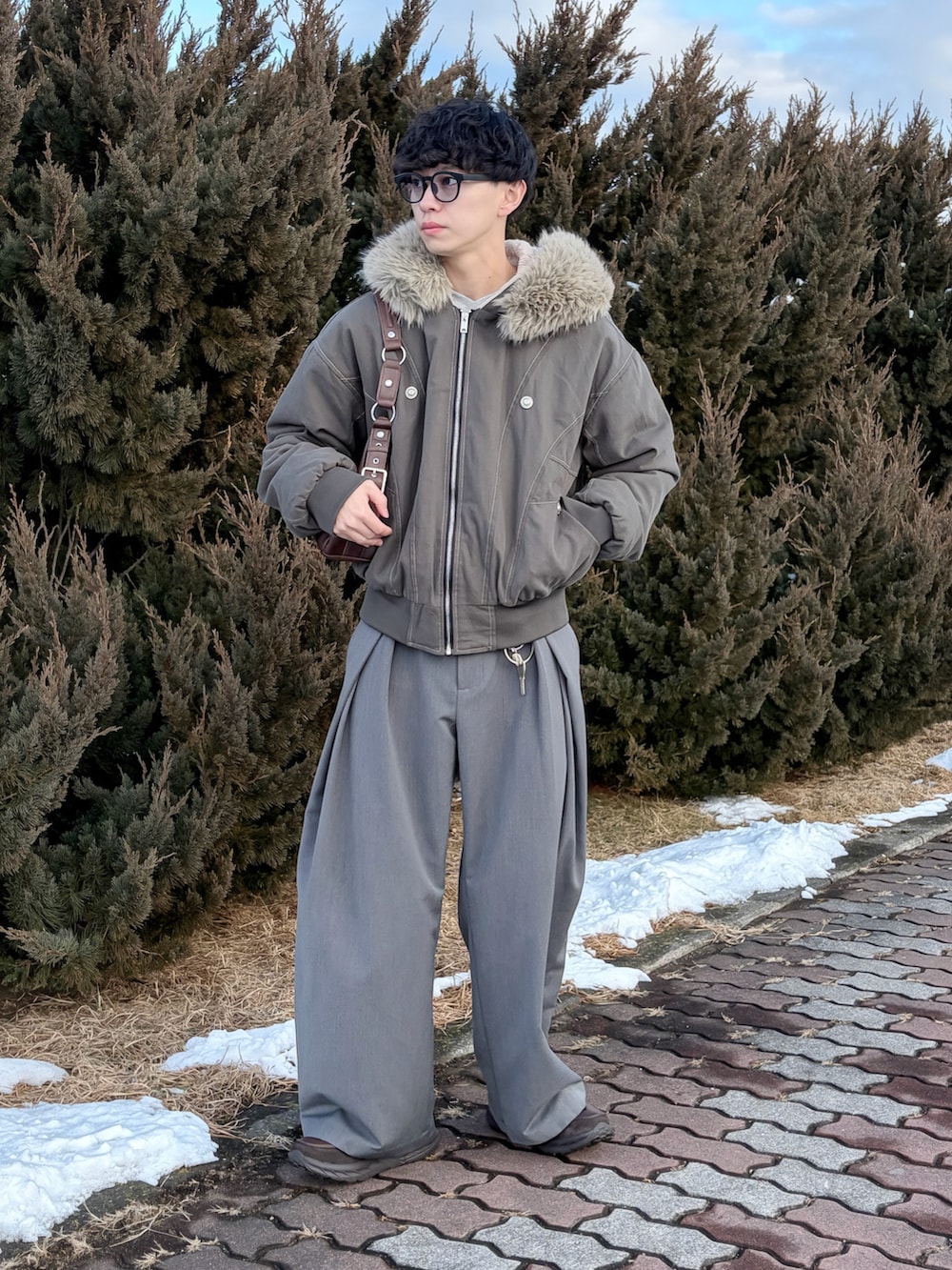 ブラウン系のブルゾン、グレー系のスウェット、グレー系のスラックスを着用したメンズの冬コーディネートの2枚目の写真