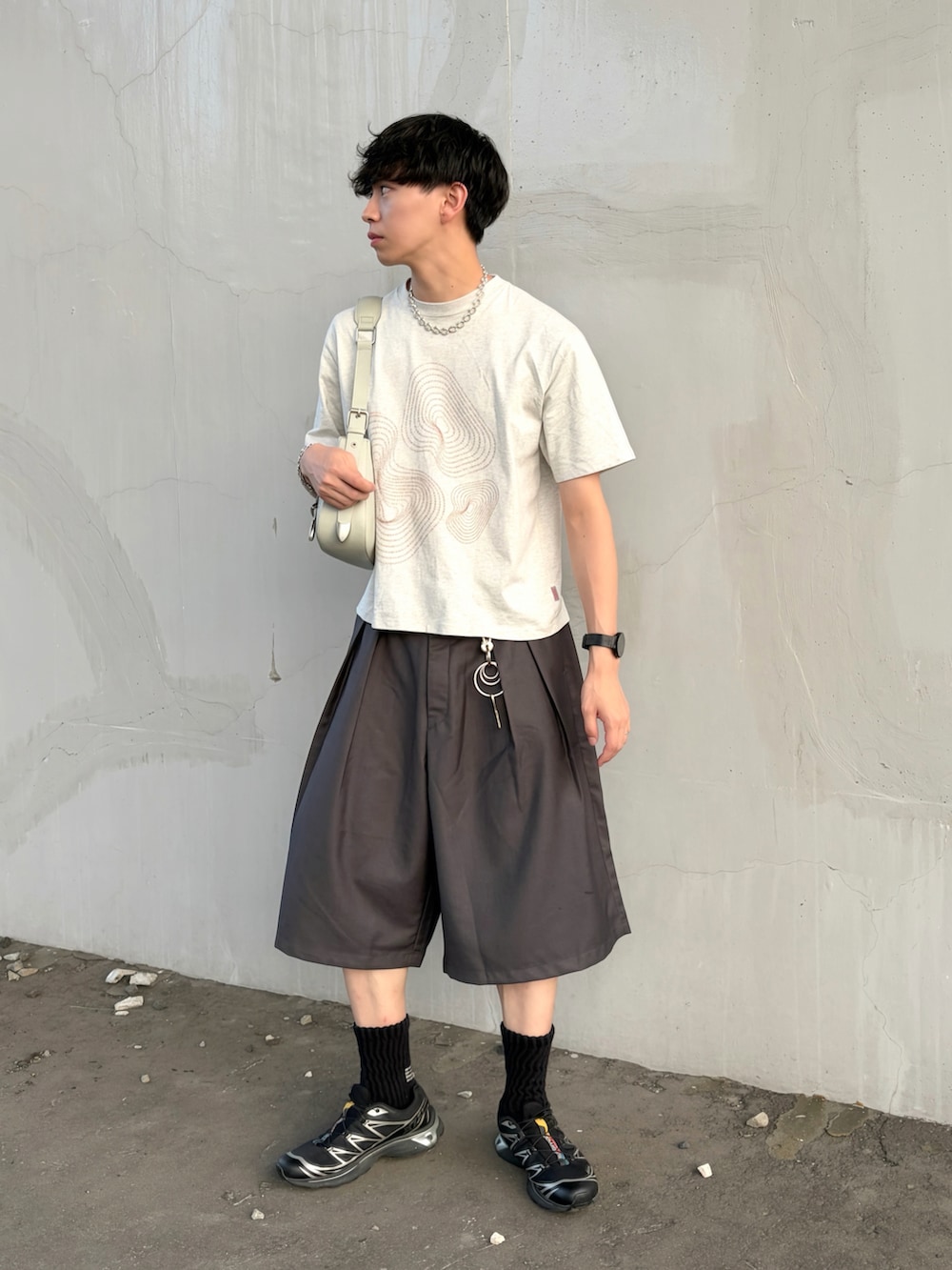 ホワイト系のTシャツ/カットソー、グレー系のスラックス、グリーン系のショルダーバッグを着用したメンズの夏コーディネートの2枚目の写真