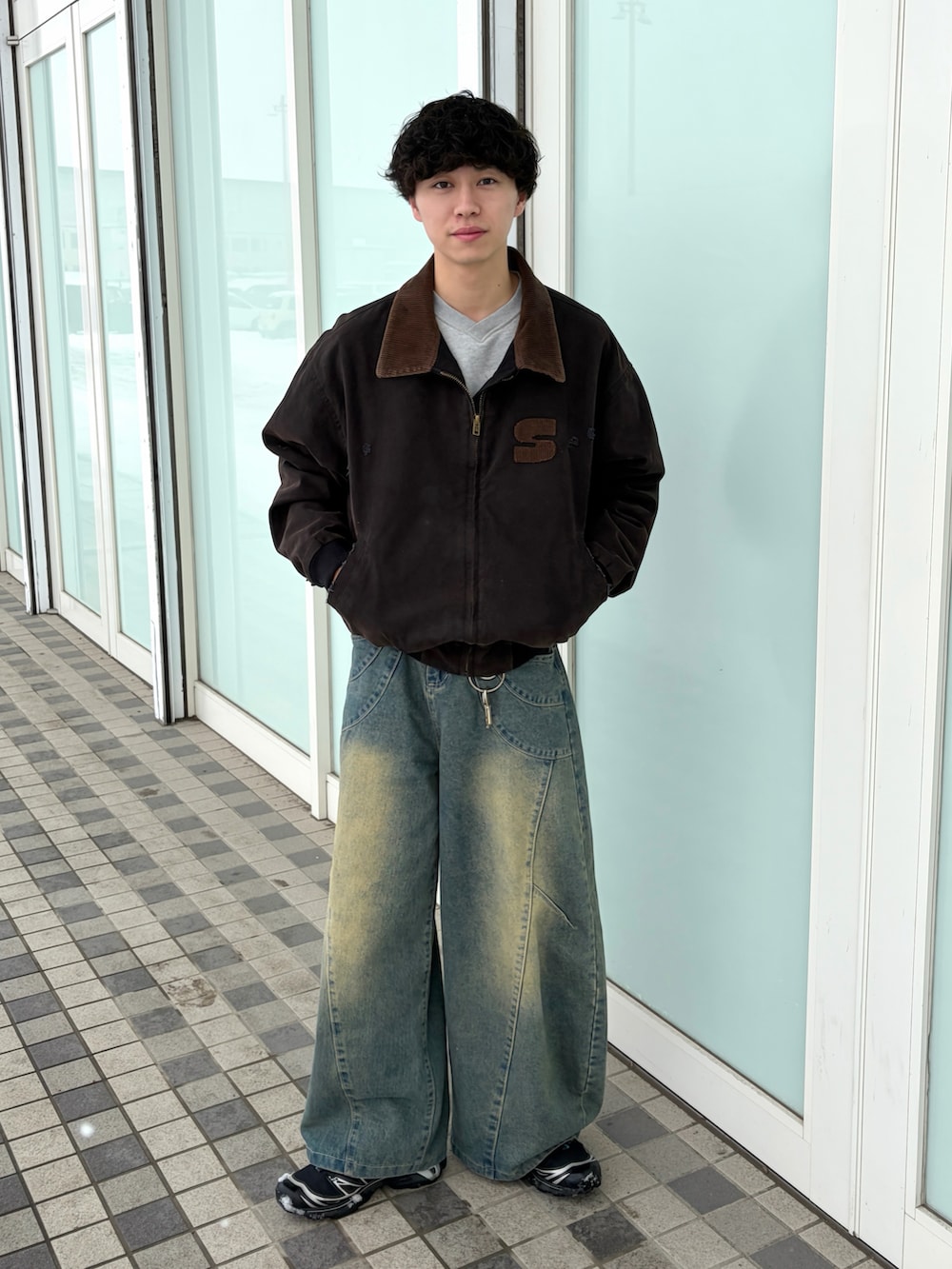 ブラック系のブルゾン、ブルー系のデニムパンツ、ブラック系のスニーカーを着用したメンズの春コーディネートの3枚目の写真