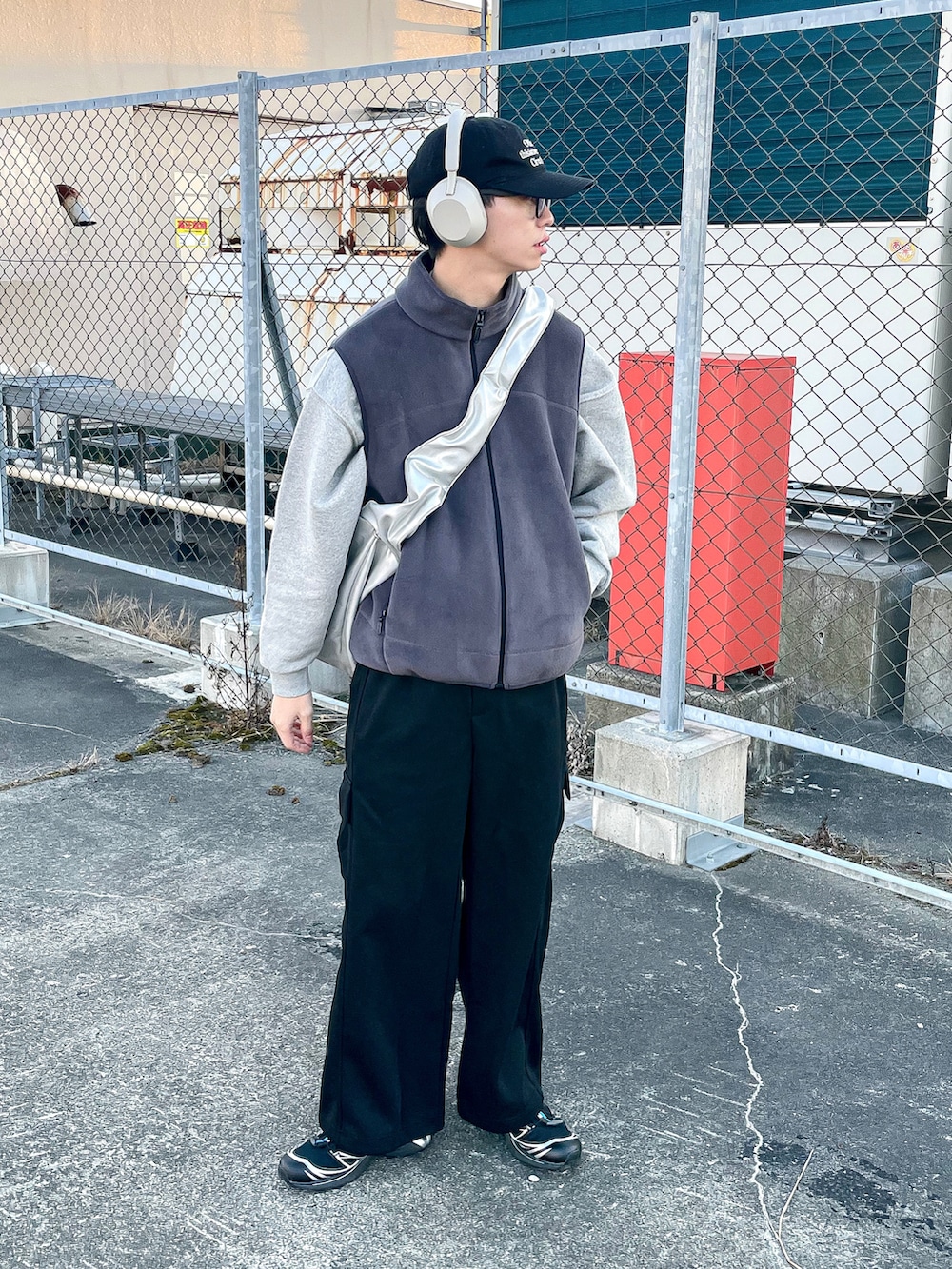 グレー系のベスト、ブラック系のカーゴパンツ、ブラック系のスニーカーを着用したメンズの冬コーディネートの2枚目の写真