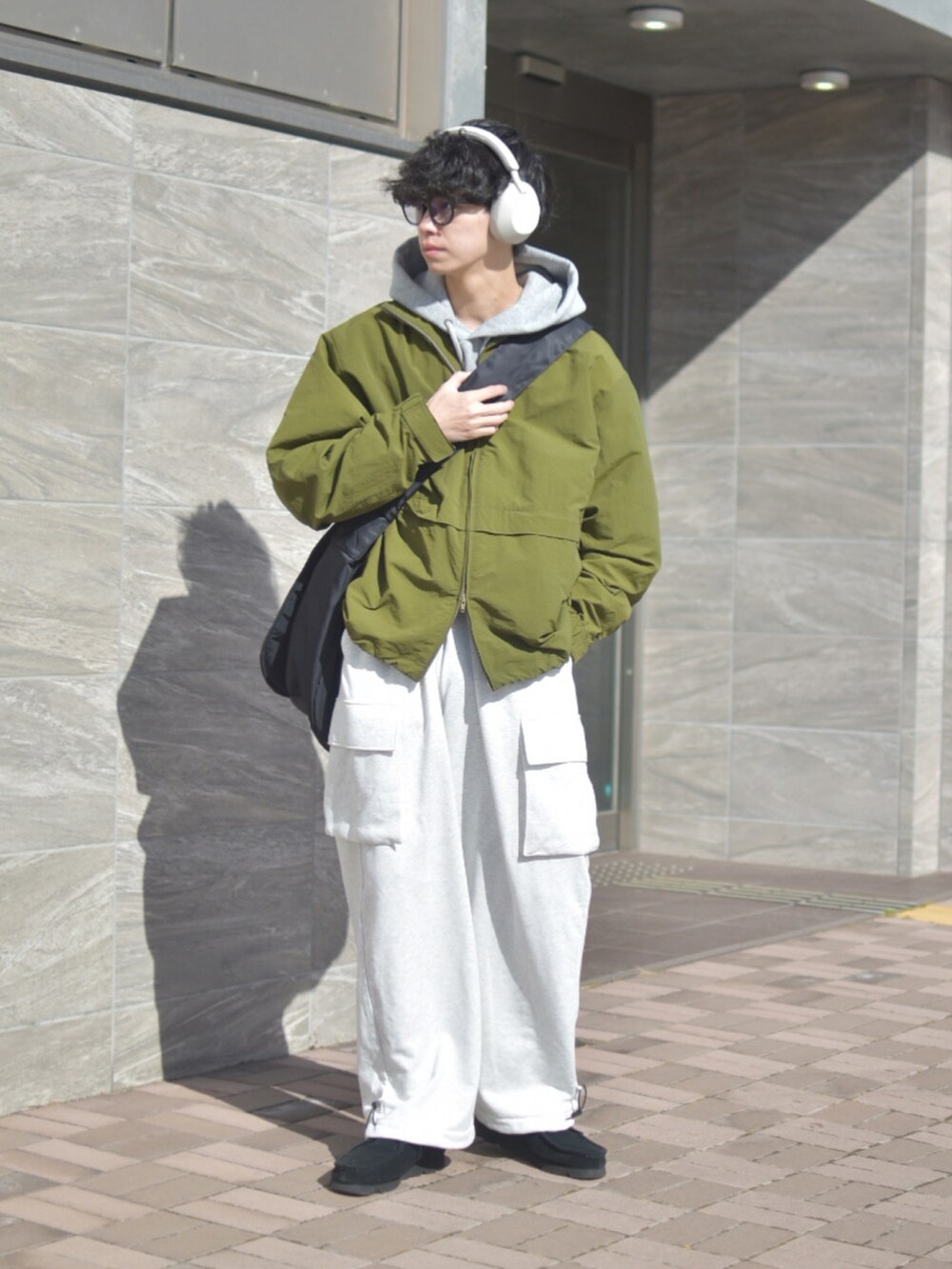 グリーン系のナイロンジャケット、ブラック系のショルダーバッグ、ホワイト系のパンツを着用したメンズの冬コーディネートの4枚目の写真
