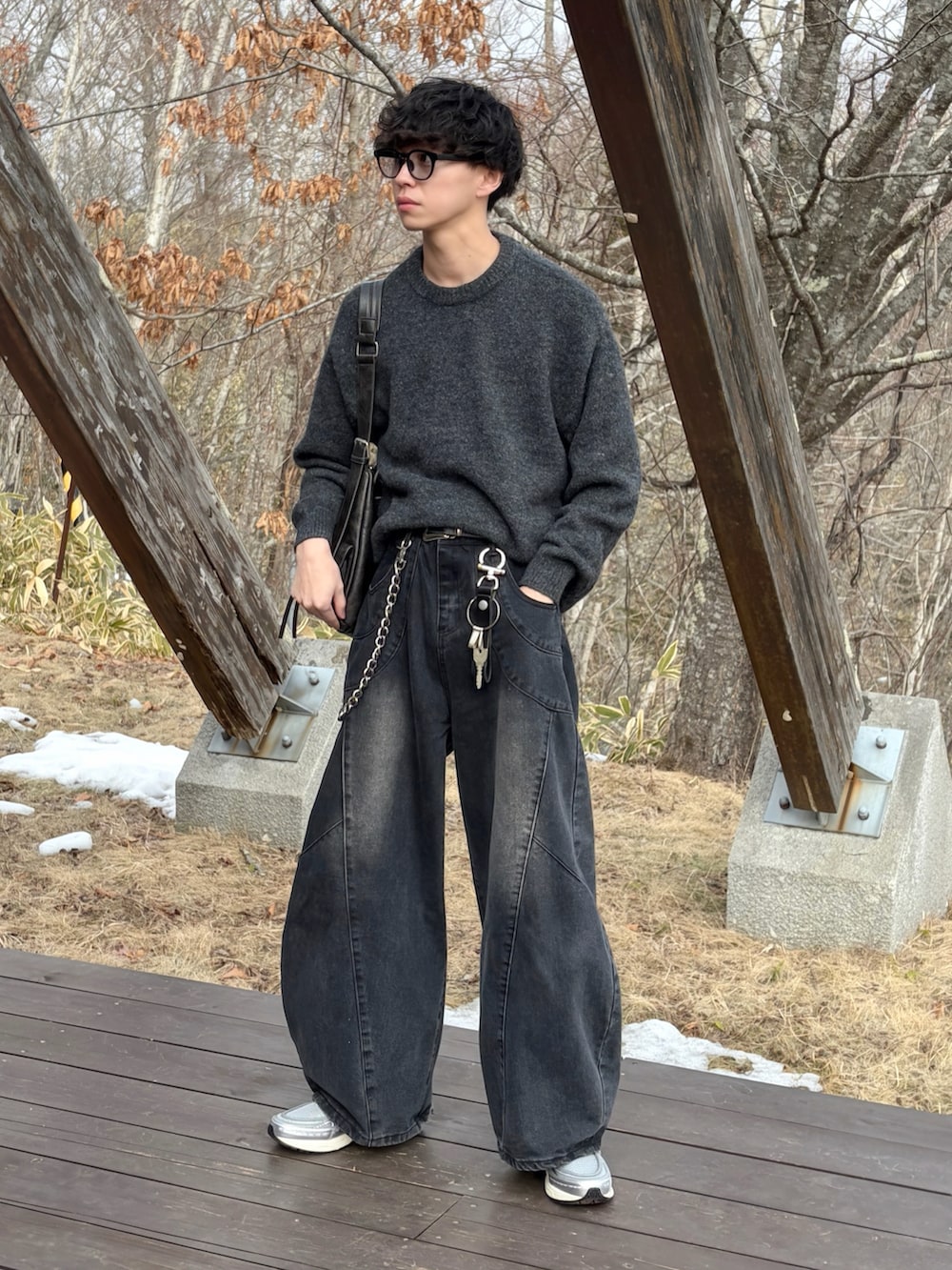 シルバー系のスニーカー、ブラック系のデニムパンツ、ブラウン系のニット/セーターを着用したメンズの冬コーディネートの2枚目の写真