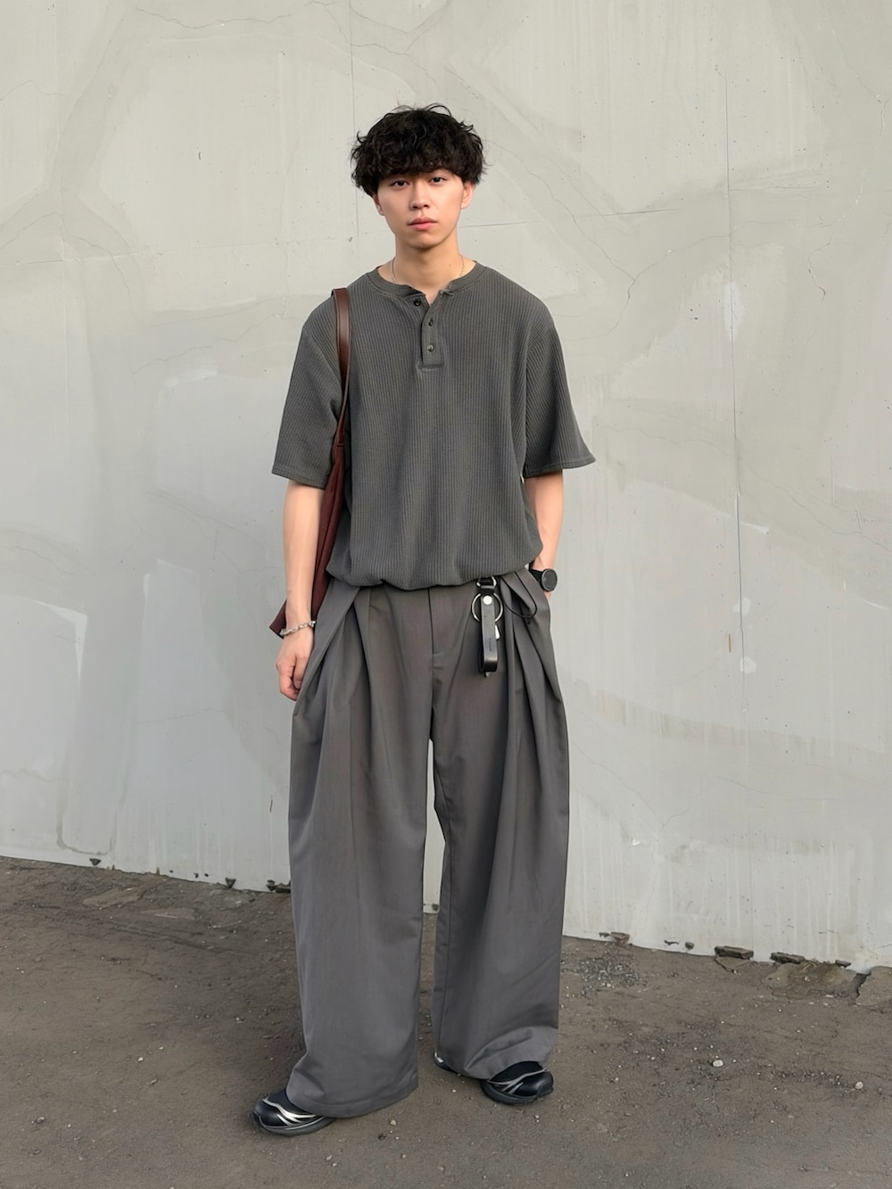 グレー系のTシャツ/カットソー、グレー系のスラックス、ブラック系のスニーカーを着用したメンズの夏コーディネートの2枚目の写真