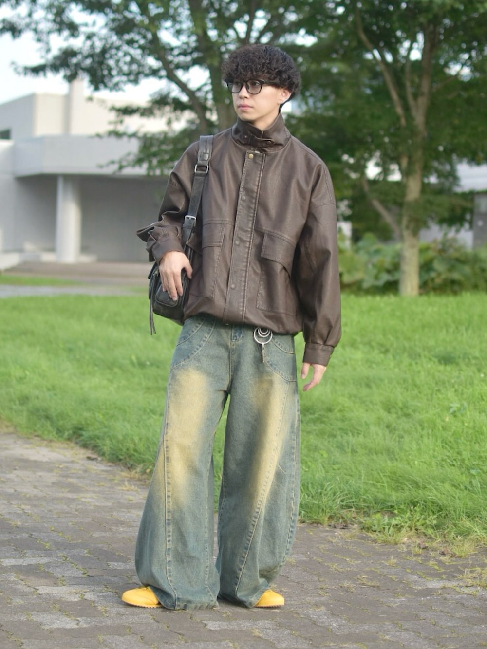 ブラウン系のブルゾン、ブルー系のデニムパンツ、イエロー系のスニーカーを着用したメンズの秋コーディネートの3枚目の写真