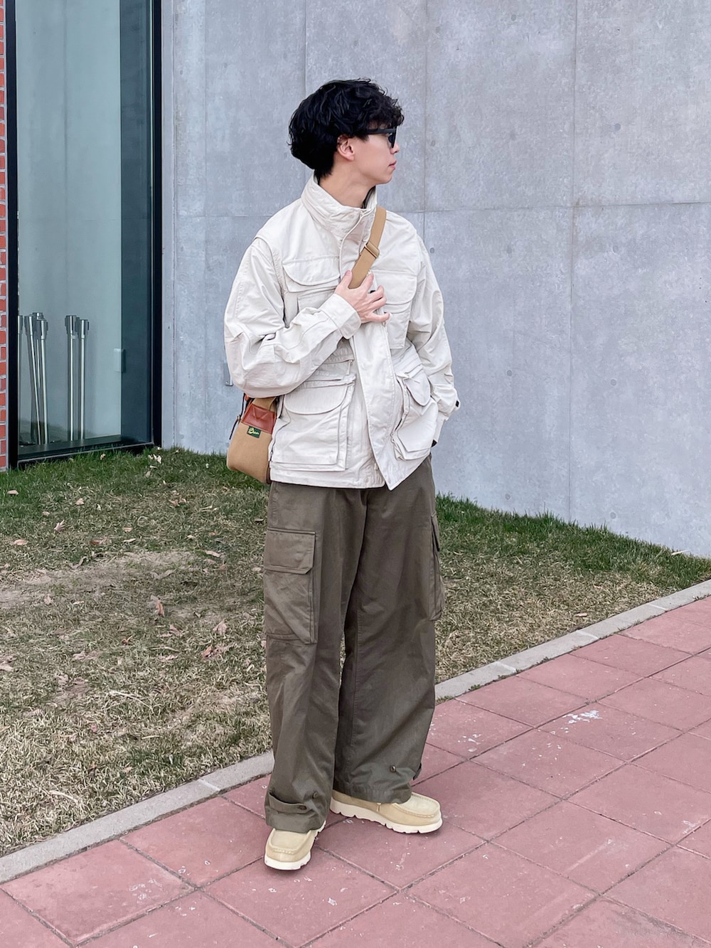 ベージュ系のブルゾン、ベージュ系のモカシン/デッキシューズ、グリーン系のカーゴパンツを着用したメンズの春コーディネートの2枚目の写真