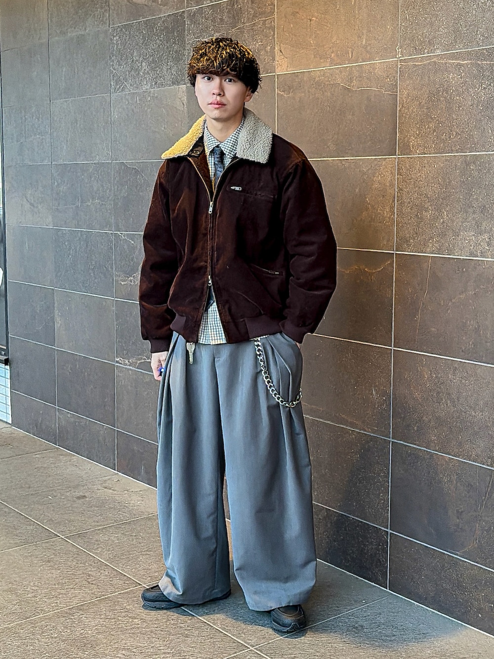 ブラウン系のブルゾン、ブラック系のネクタイ、グレー系のスラックスを着用したメンズの冬コーディネートの2枚目の写真