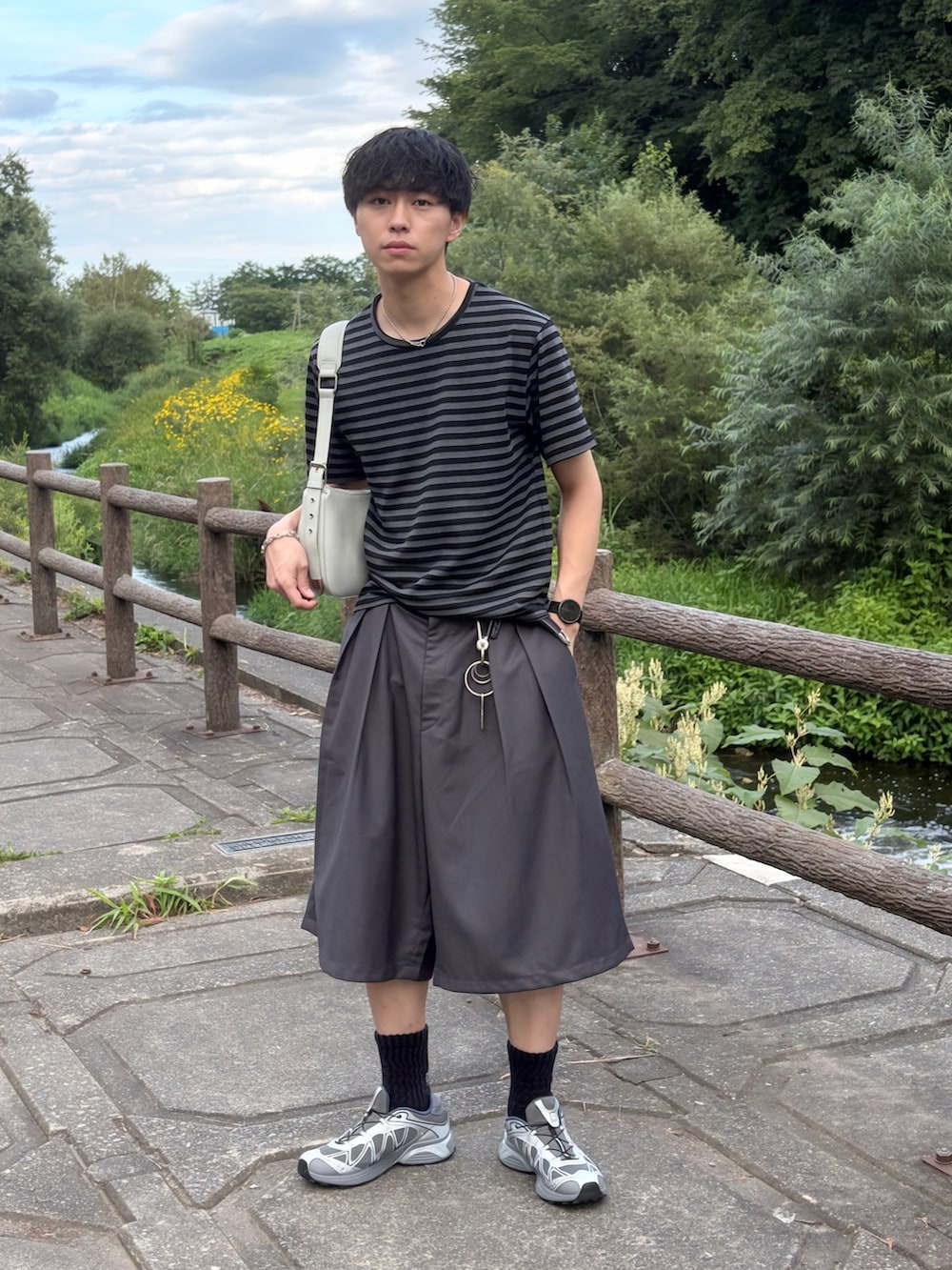 ブラック系のTシャツ/カットソー、グレー系のスニーカー、グレー系のスラックスを着用したメンズの夏コーディネートの2枚目の写真