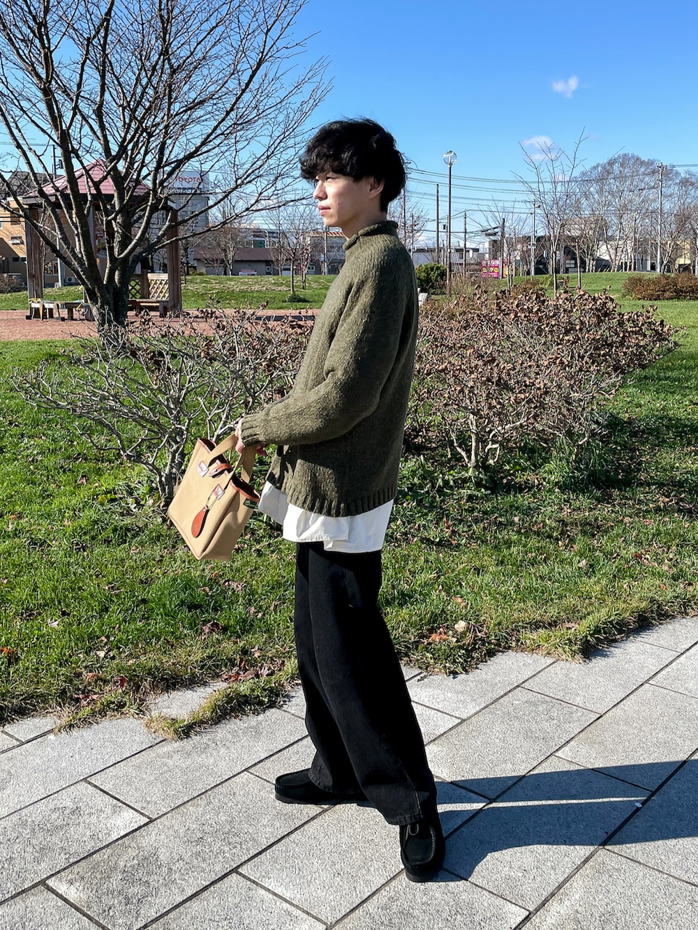 グリーン系のニット/セーター、ブラック系のデニムパンツ、ブラック系のモカシン/デッキシューズを着用したメンズの秋コーディネートの4枚目の写真