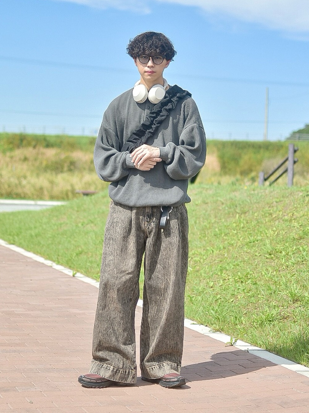 グレー系のTシャツ/カットソー、ブラウン系のデニムパンツ、ブラウン系のスニーカーを着用したメンズの秋コーディネートの4枚目の写真