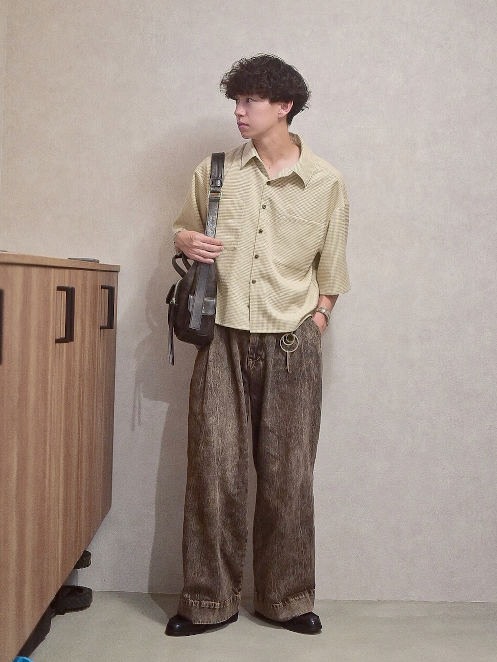 ブラック系のデニムパンツ、ベージュ系のシャツ/ブラウス、ブラック系のショルダーバッグを着用したメンズの秋コーディネートの3枚目の写真