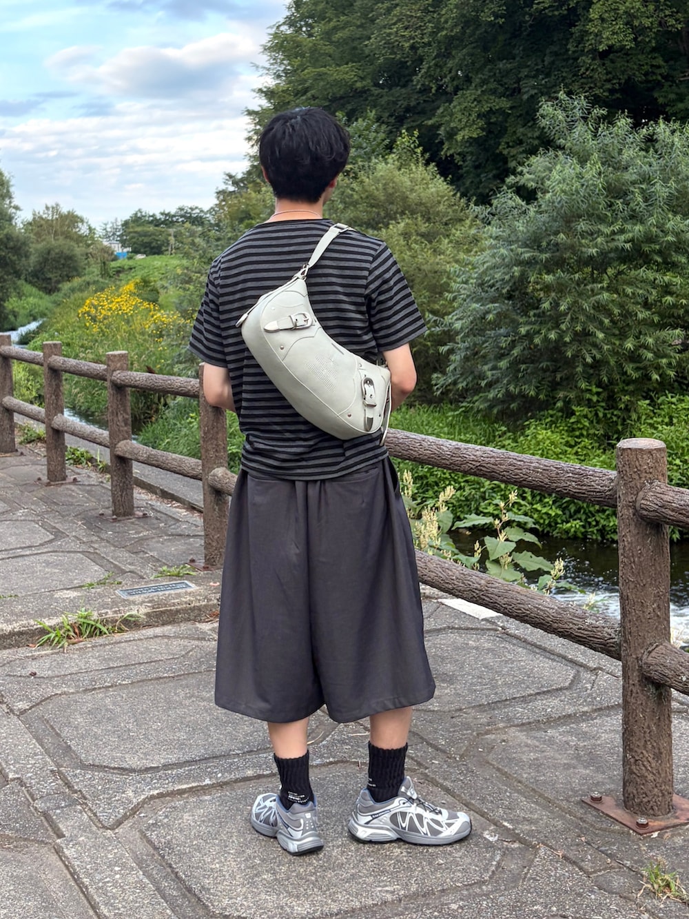 ブラック系のTシャツ/カットソー、グレー系のスニーカー、グレー系のスラックスを着用したメンズの夏コーディネートの3枚目の写真