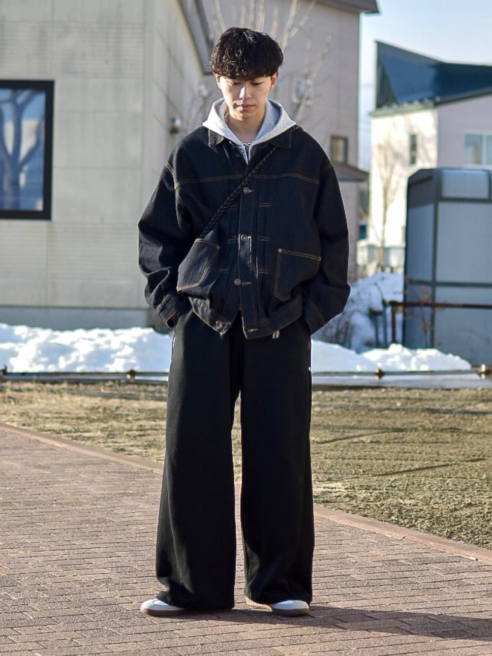 ブルー系のデニムジャケット、グレー系のパーカー、ブラック系のスウェットパンツを着用したメンズの春コーディネートの2枚目の写真