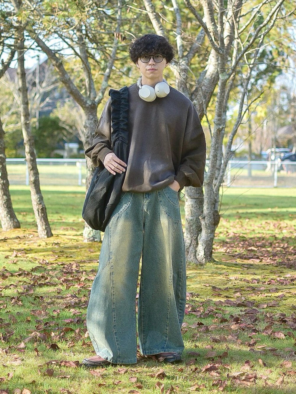 ブラウン系のスウェット、ブルー系のデニムパンツ、ブラック系のショルダーバッグを着用したメンズの秋コーディネートの3枚目の写真