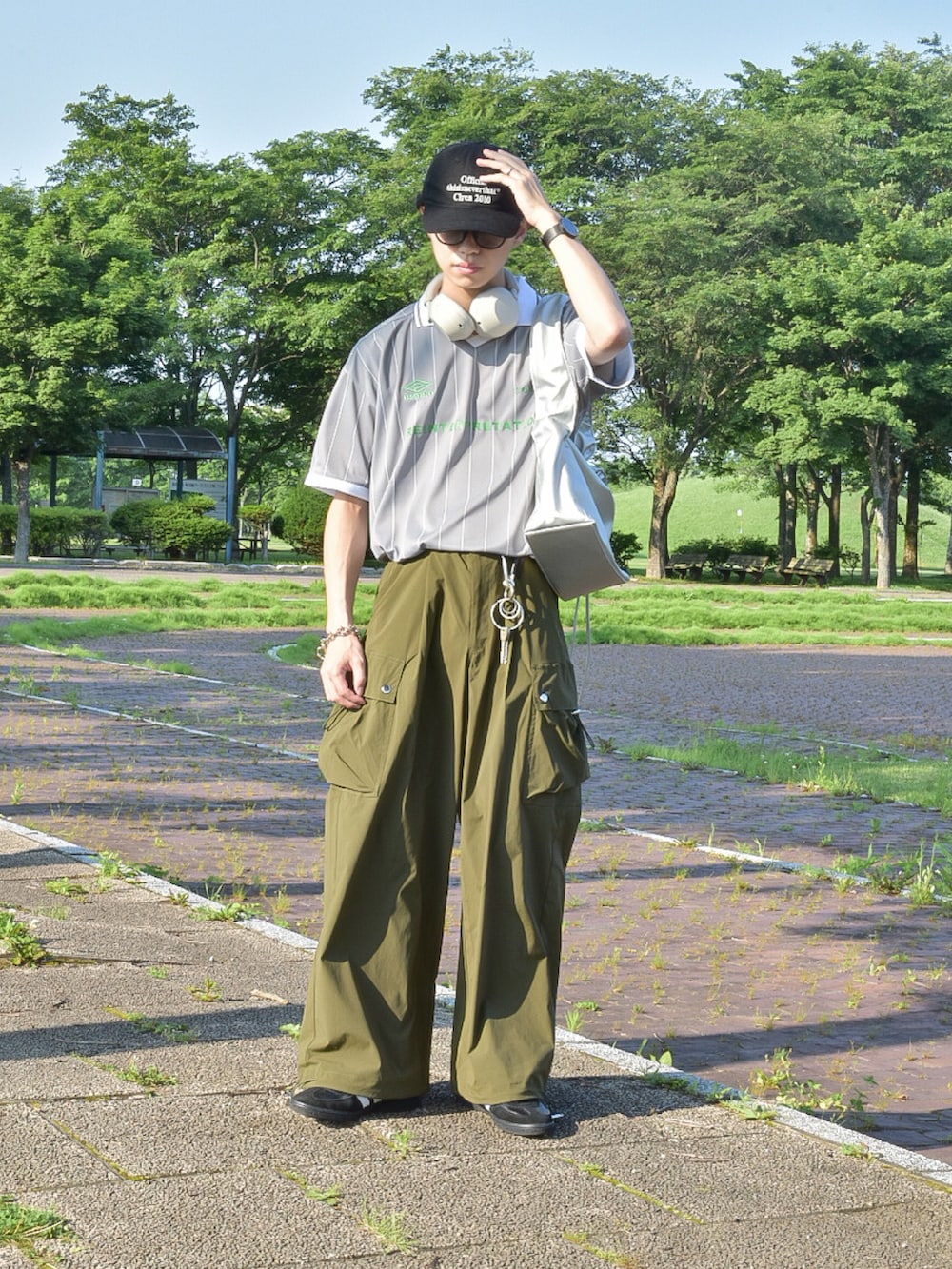 グレー系のTシャツ/カットソー、グリーン系のカーゴパンツ、ブラック系のスニーカーを着用したメンズの夏コーディネートの2枚目の写真