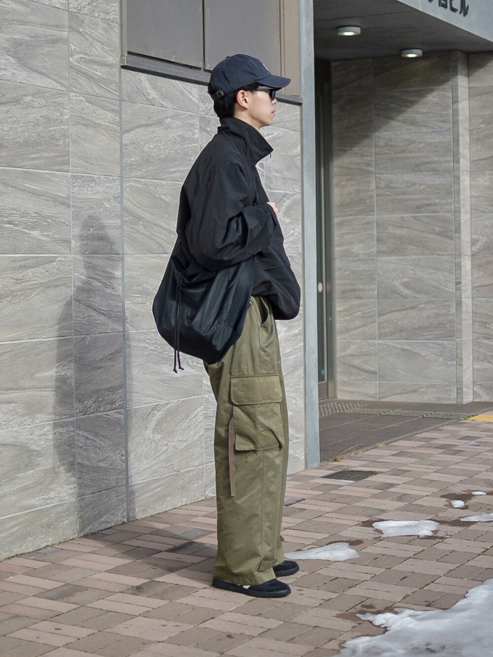 ブラック系のナイロンジャケット、グリーン系のカーゴパンツ、ブラック系のスニーカーを着用したメンズの冬コーディネートの4枚目の写真