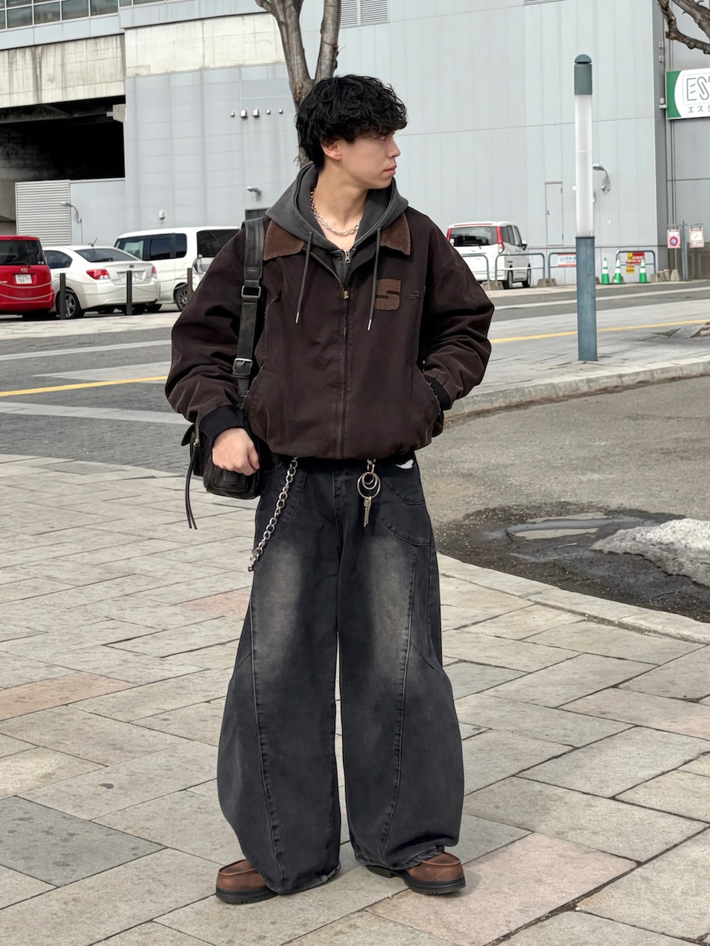 ブラック系のブルゾン、ブラック系のデニムパンツ、ブラウン系のブーツを着用したメンズの春コーディネートの2枚目の写真