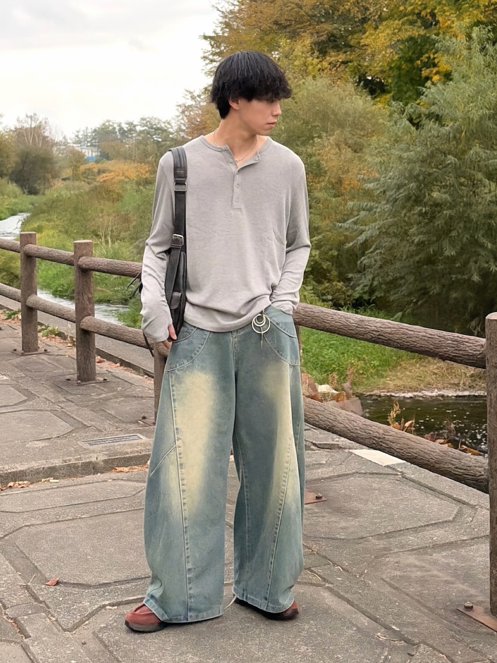 グレー系のニット/セーター、ブルー系のデニムパンツ、ブラウン系のスニーカーを着用したメンズの秋コーディネートの2枚目の写真