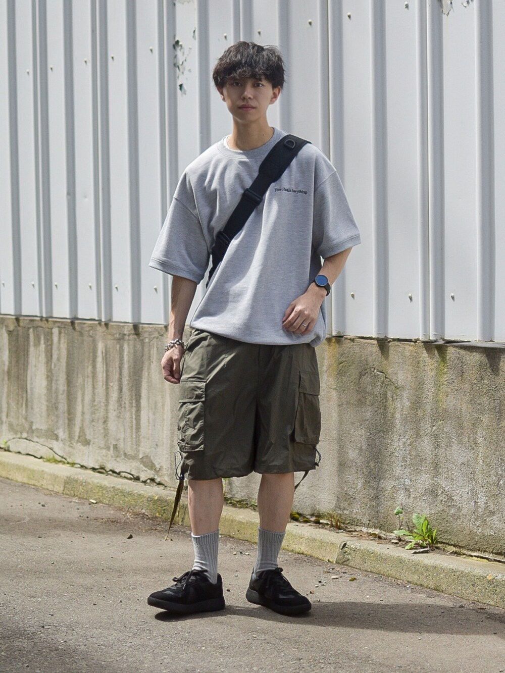 グレー系のTシャツ/カットソー、グリーン系のカーゴパンツ、ブラック系のスニーカーを着用したメンズの夏コーディネートの3枚目の写真