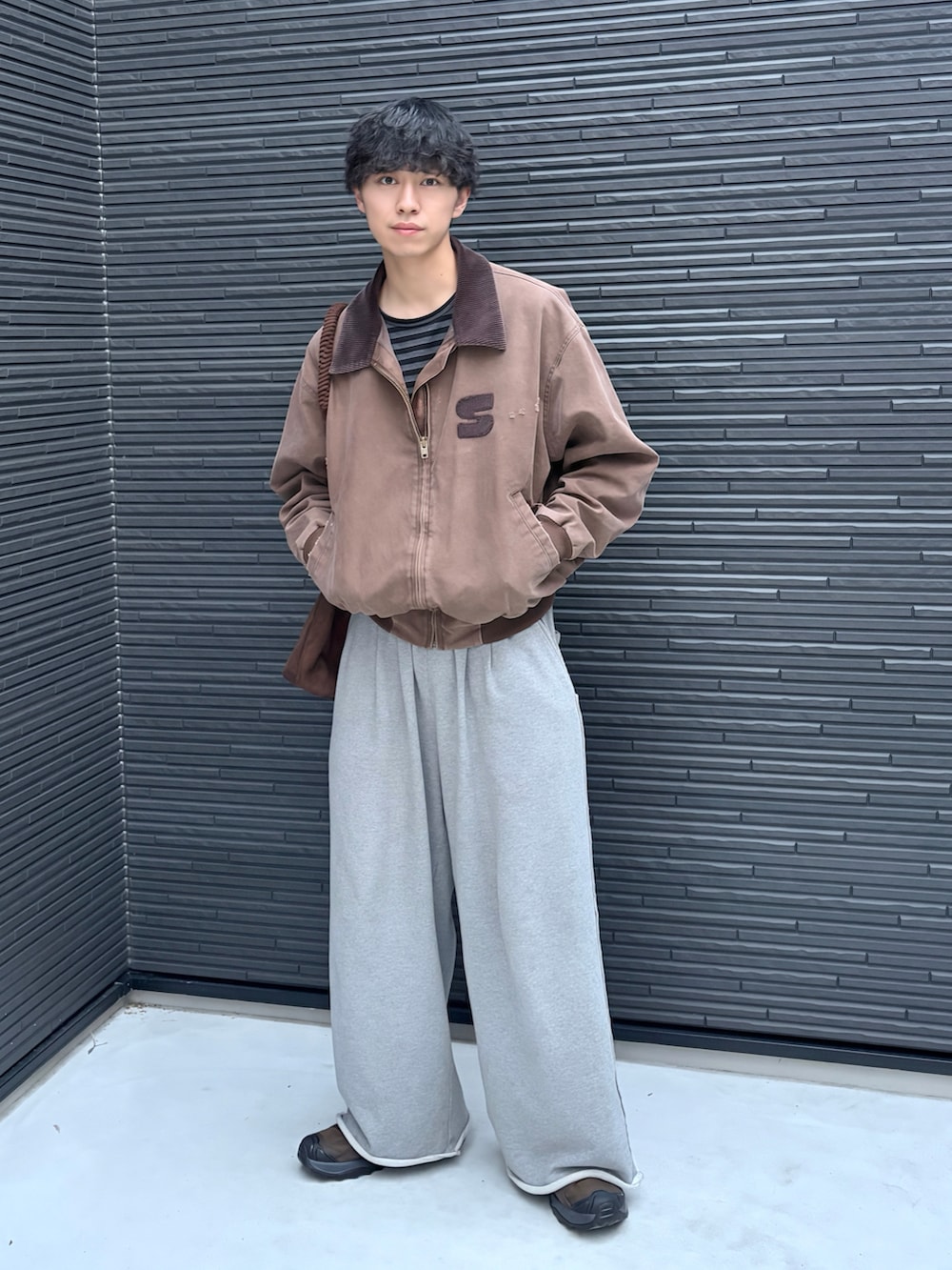 ブラウン系のトートバッグ、ブラウン系のスニーカー、ブラック系のTシャツ/カットソーを着用したメンズの秋コーディネートの2枚目の写真