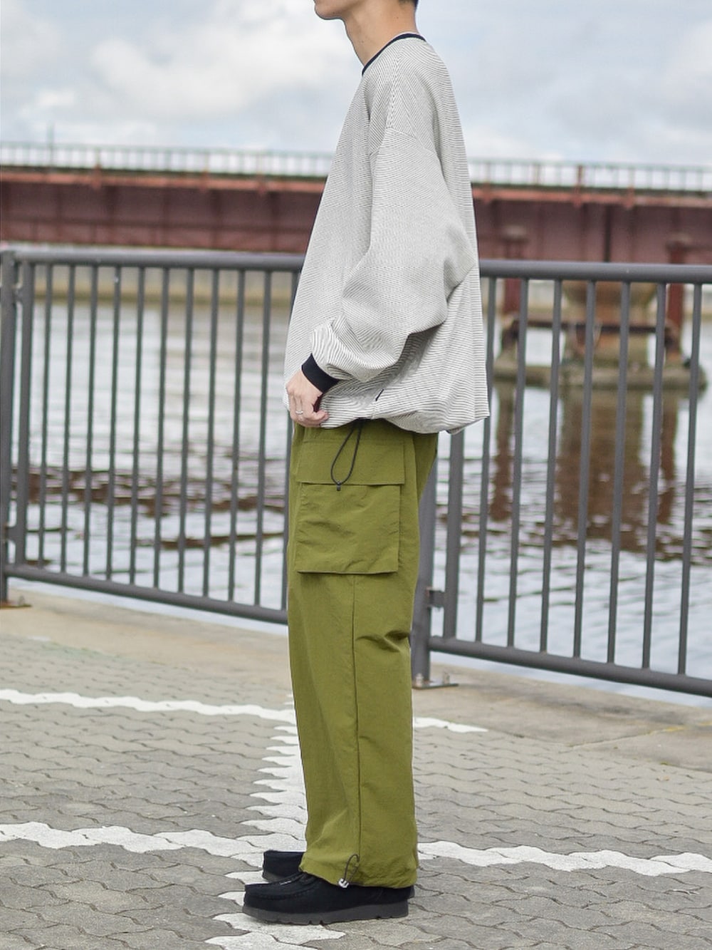 ブラック系のトップス、ブラック系のモカシン/デッキシューズ、グリーン系のカーゴパンツを着用したメンズの秋コーディネートの3枚目の写真