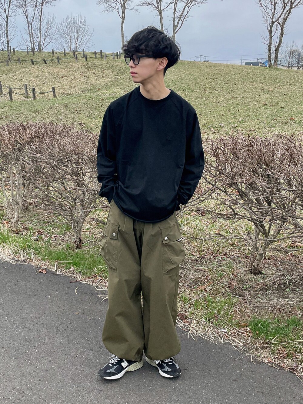 グレー系のベスト、ブラック系のTシャツ/カットソー、グリーン系のカーゴパンツを着用したメンズの春コーディネートの5枚目の写真