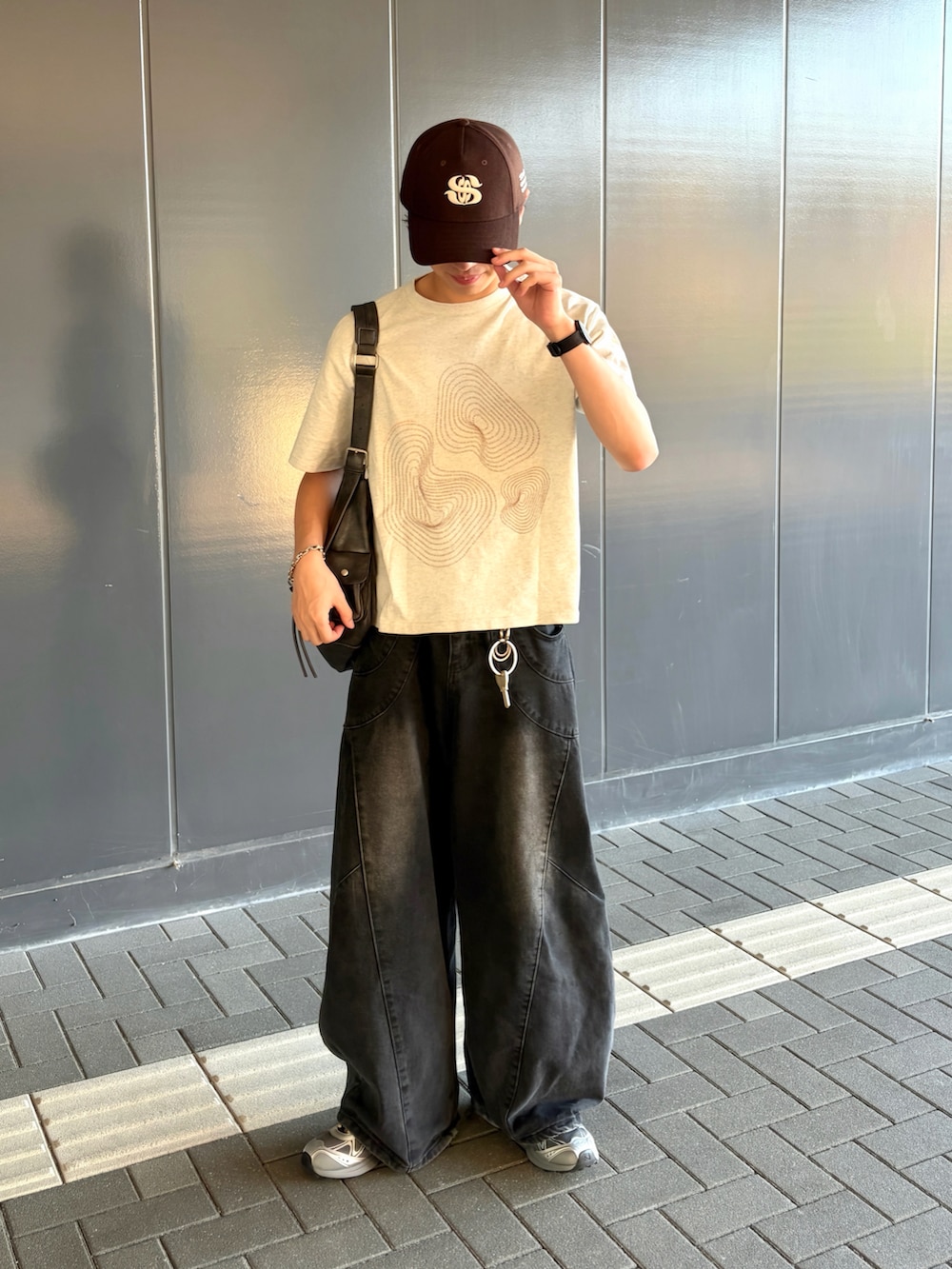 ブラック系のデニムパンツ、グレー系のスニーカー、ホワイト系のTシャツ/カットソーを着用したメンズの夏コーディネートの2枚目の写真