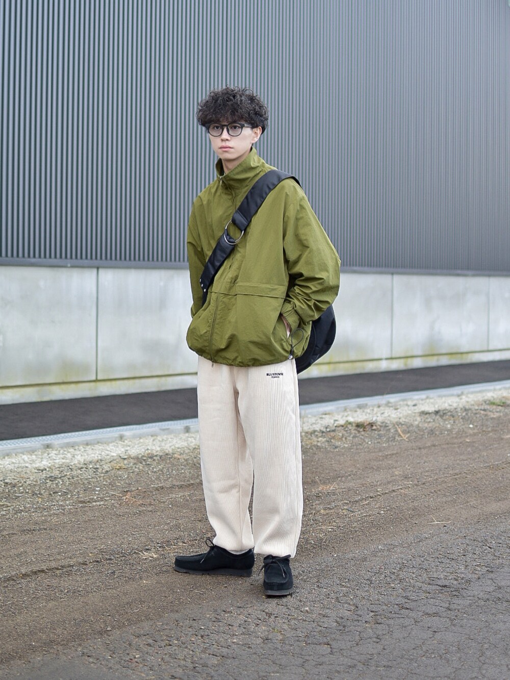 グリーン系のナイロンジャケット、ホワイト系のパンツ、ブラック系のショルダーバッグを着用したメンズの冬コーディネートの3枚目の写真