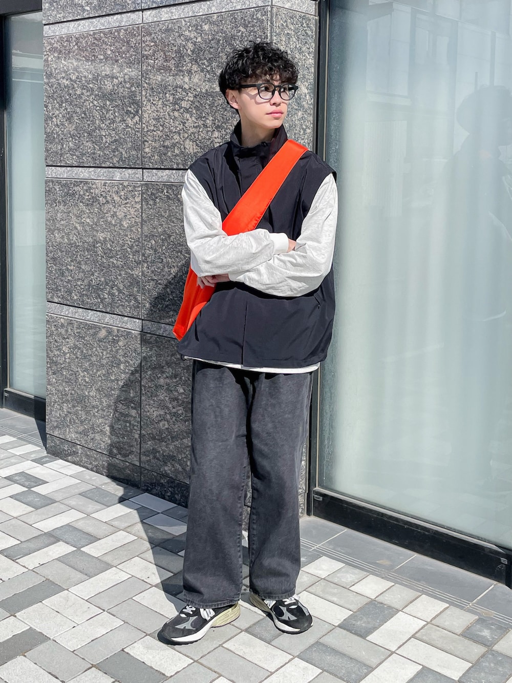 ブラック系のブルゾン、ブラック系のデニムパンツ、オレンジ系のショルダーバッグを着用したメンズの春コーディネートの2枚目の写真