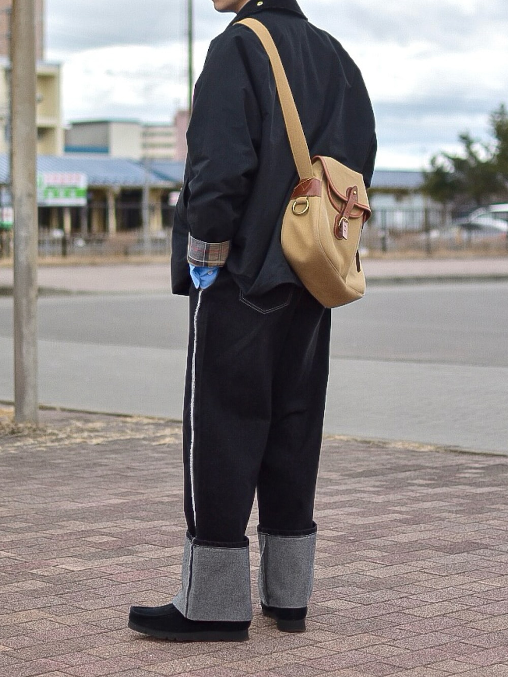 ブラック系のデニムパンツ、ブラック系のステンカラーコート、ブルー系のシャツ/ブラウスを着用したメンズの春コーディネートの2枚目の写真