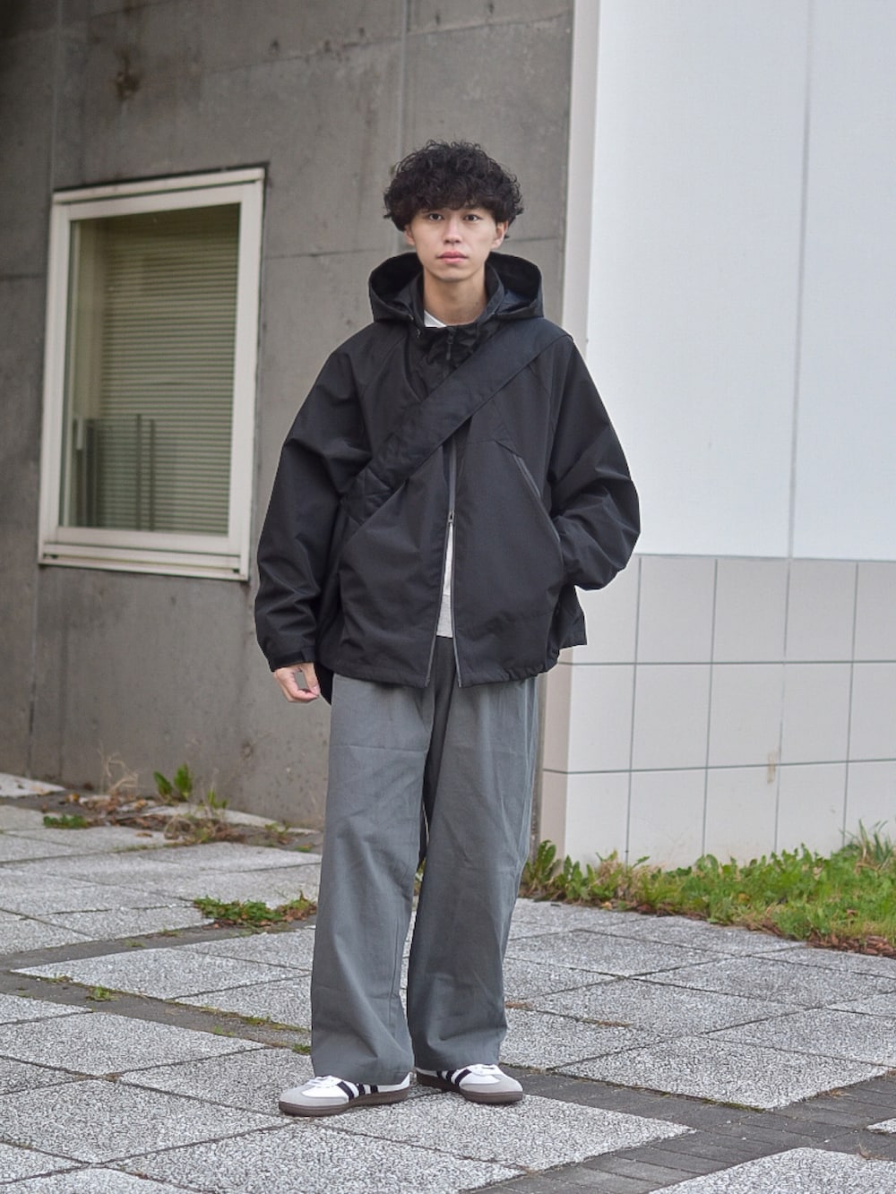グレー系のデニムパンツ、ブラック系のブルゾン、ベージュ系のスウェットを着用したメンズの秋コーディネートの3枚目の写真