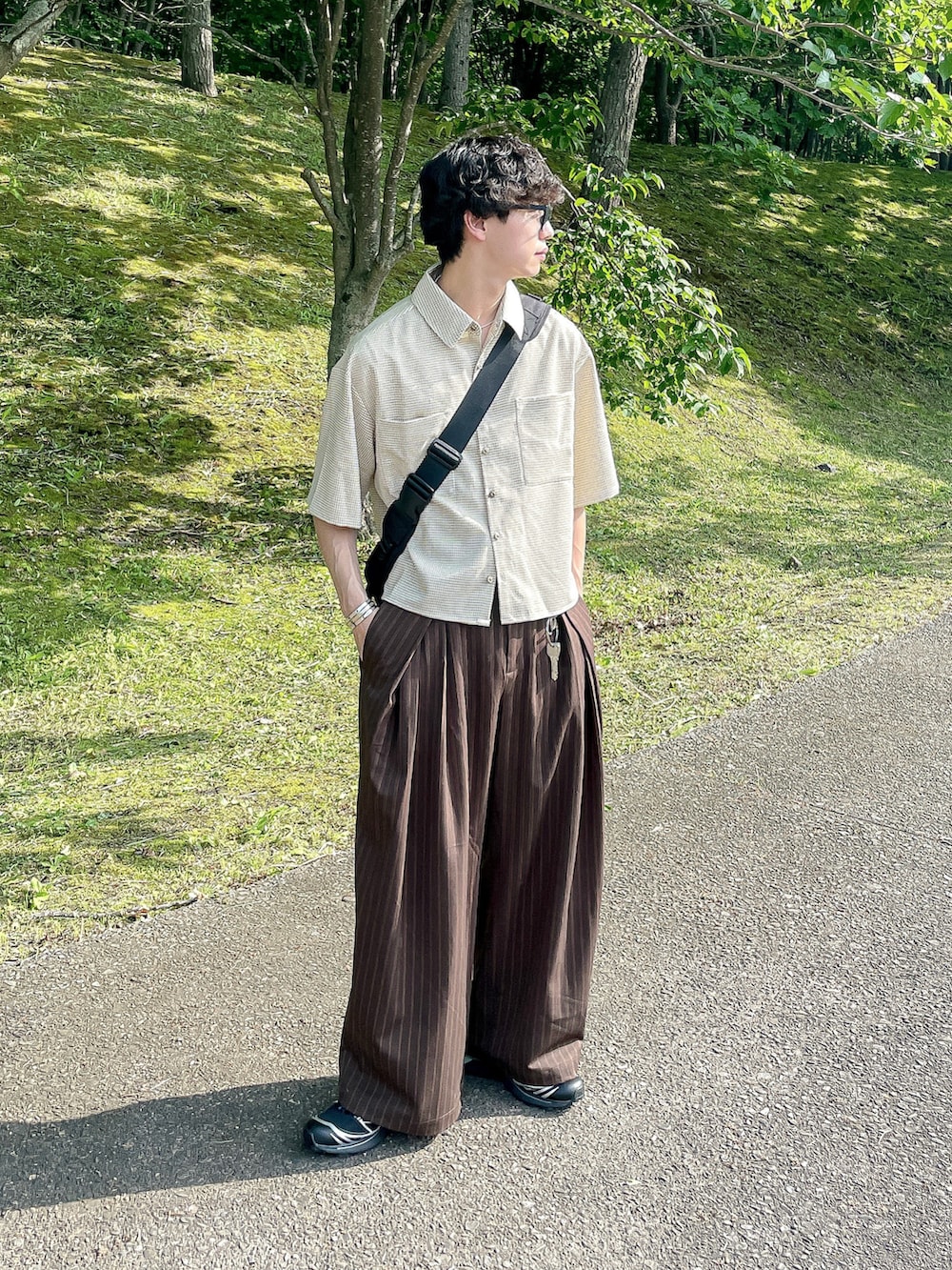 ベージュ系のシャツ/ブラウス、ブラウン系のスラックス、ブラック系のスニーカーを着用したメンズの夏コーディネートの2枚目の写真