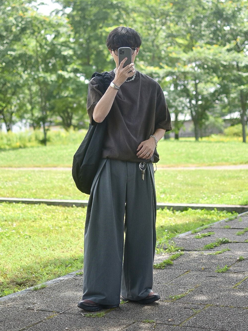 ブラウン系のTシャツ/カットソー、グレー系のスラックス、ブラウン系のスニーカーを着用したメンズの夏コーディネートの2枚目の写真