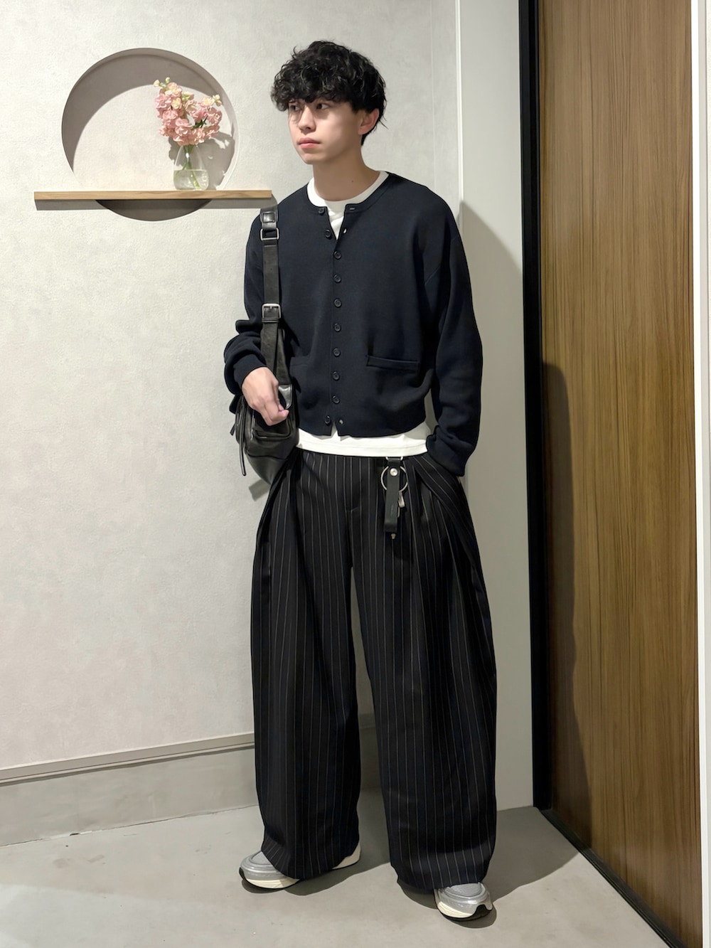 ブラック系のカーディガン/ボレロ、ホワイト系のTシャツ/カットソー、ブラック系のスラックスを着用したメンズの春コーディネートの2枚目の写真