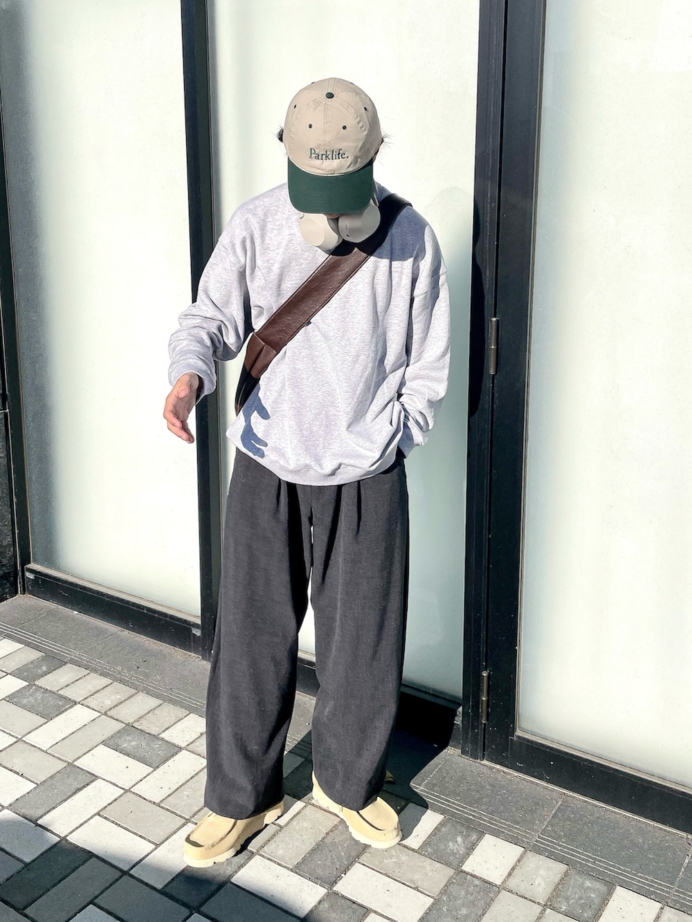 グレー系のスウェット、グレー系のスラックス、ベージュ系のモカシン/デッキシューズを着用したメンズの秋コーディネートの3枚目の写真