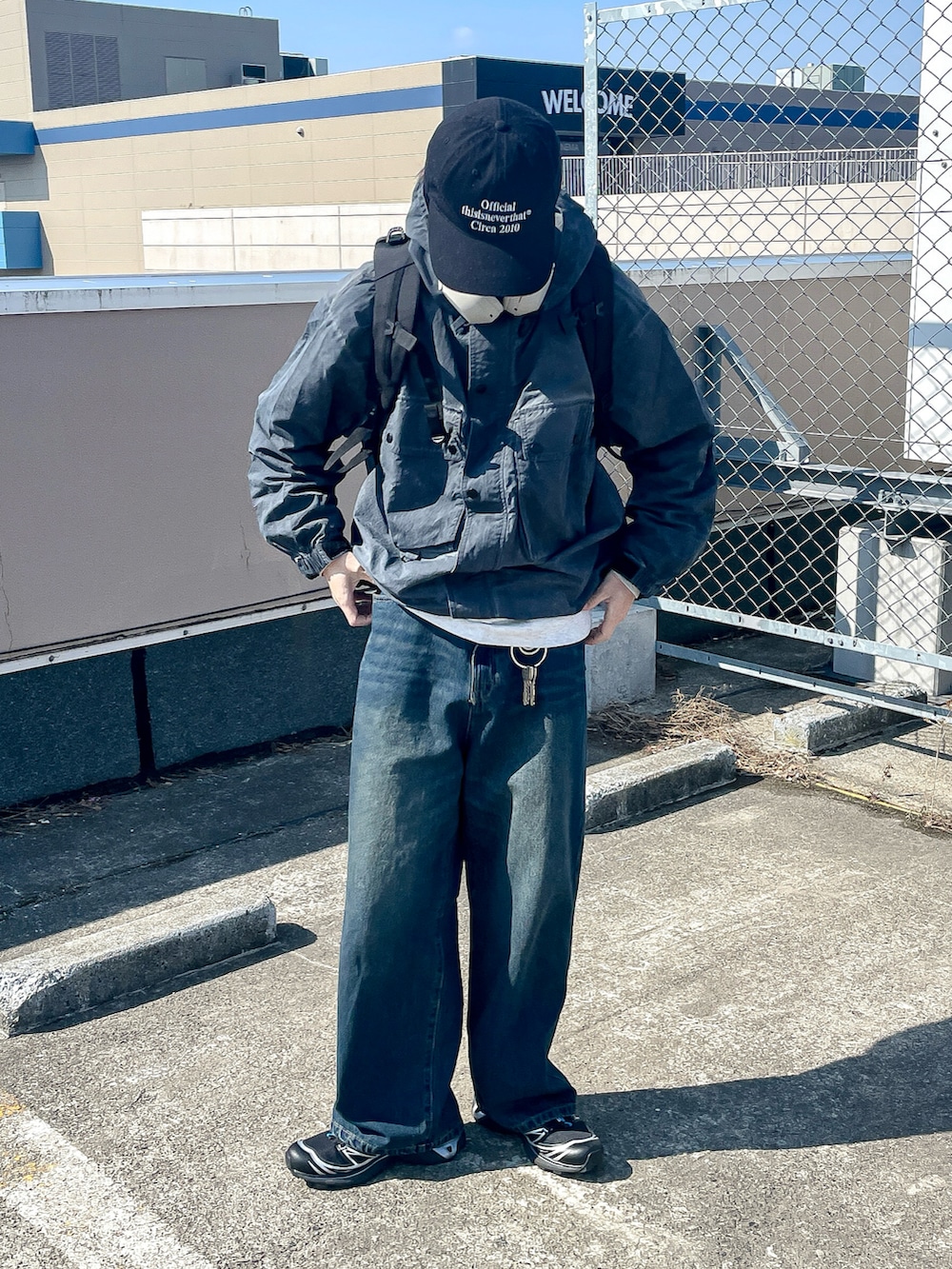 グレー系のマウンテンパーカー、ブルー系のデニムパンツ、ブラック系のスニーカーを着用したメンズの春コーディネートの3枚目の写真