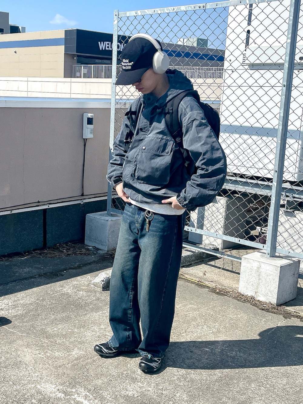 グレー系のマウンテンパーカー、ブルー系のデニムパンツ、ブラック系のスニーカーを着用したメンズの春コーディネートの2枚目の写真