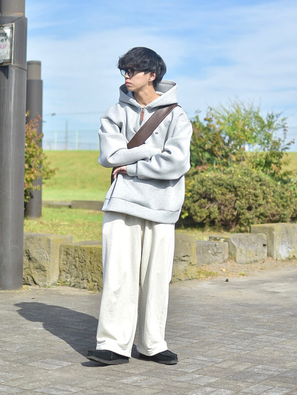 ブラック系のブルゾン、グレー系のパーカー、ホワイト系のスウェットパンツを着用したメンズの秋コーディネートの3枚目の写真